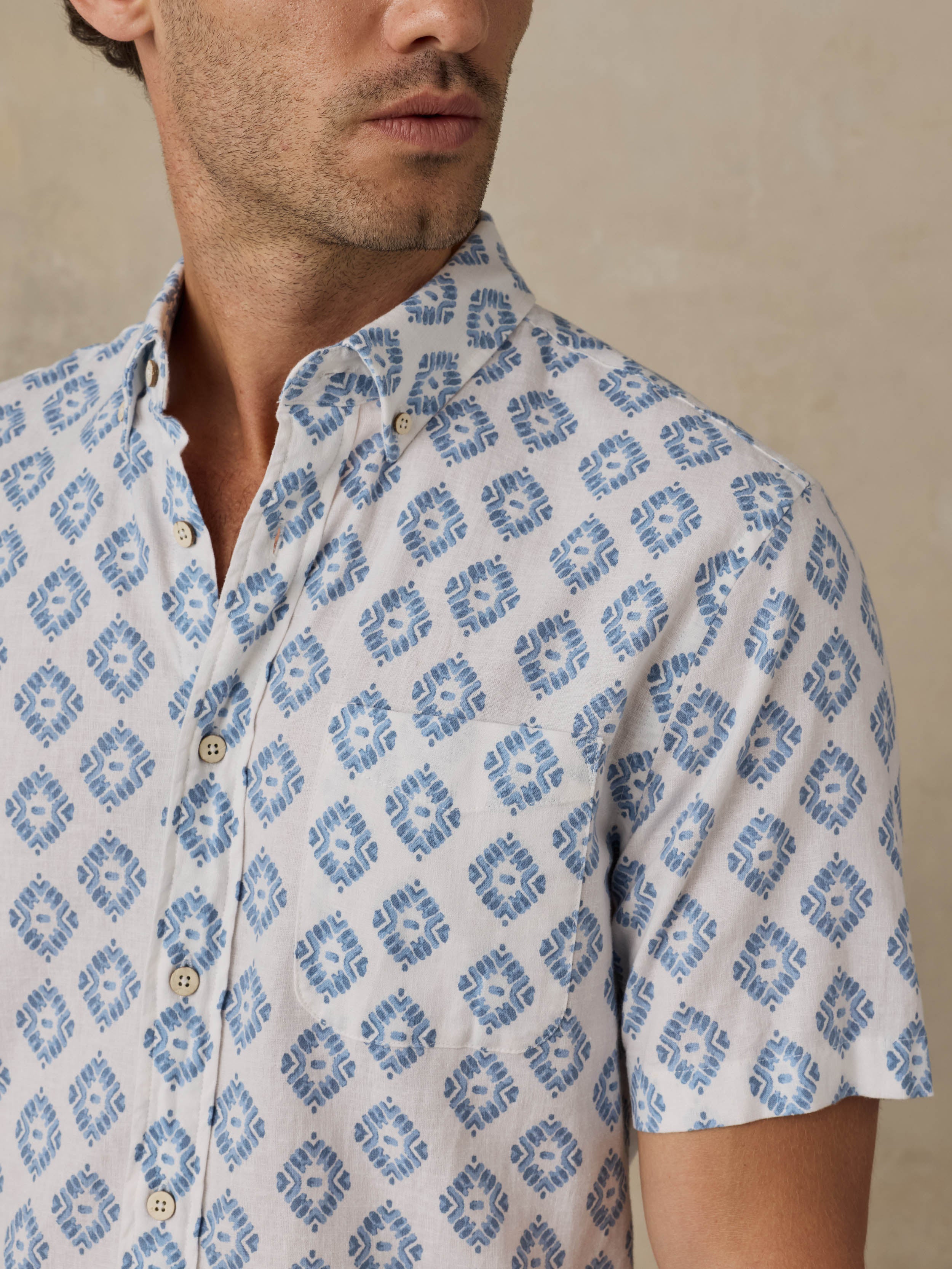 Man wearing a patterned blue and white shirt against a beige background