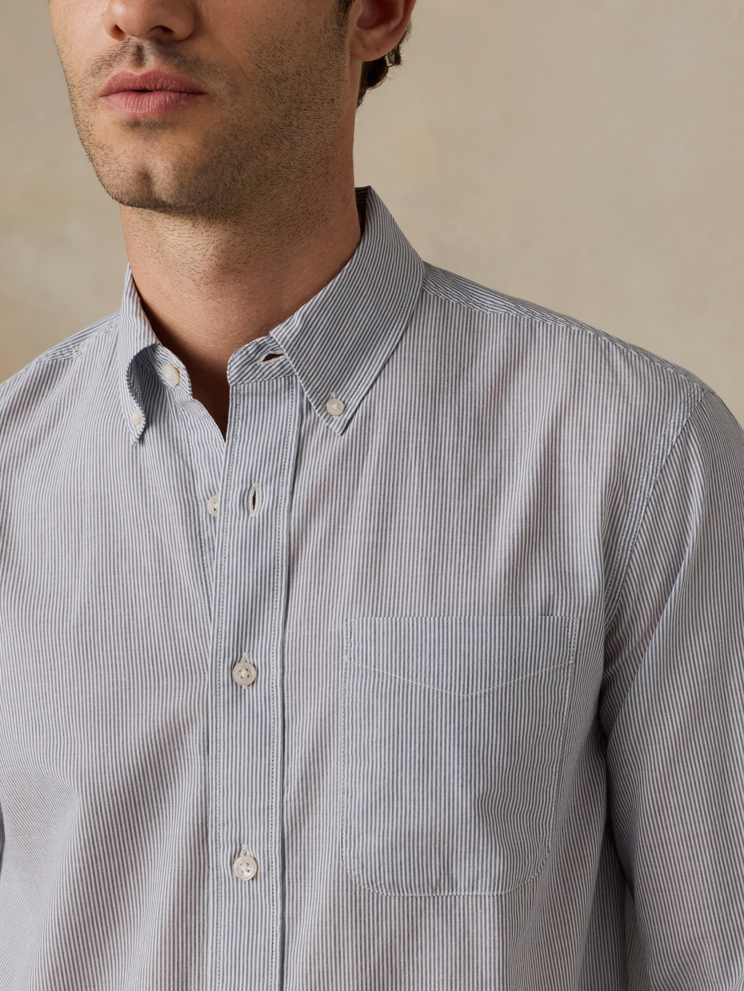 Man wearing a blue striped shirt against a neutral background