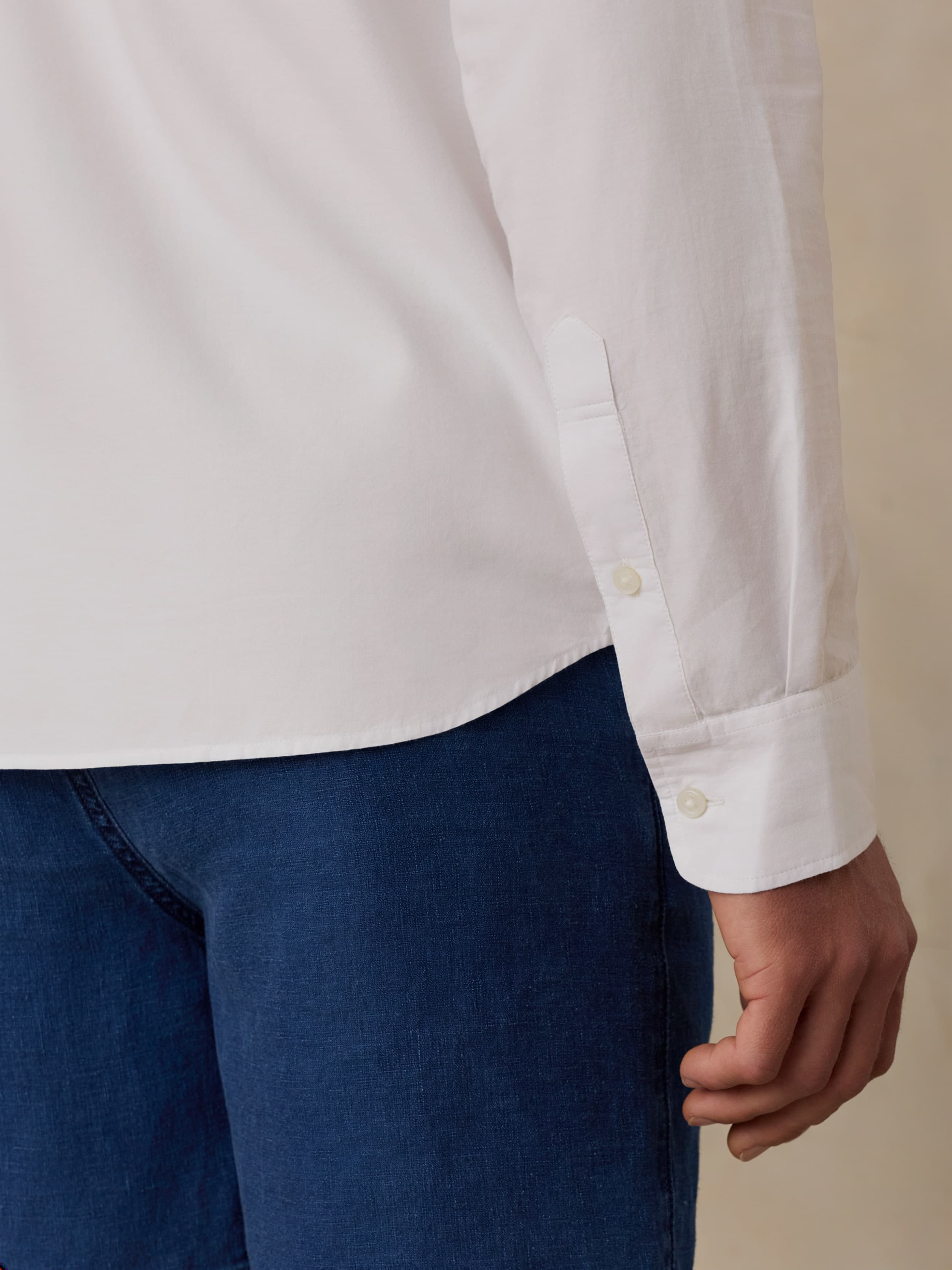 White shirt with rolled-up sleeves and blue shorts on a beige background