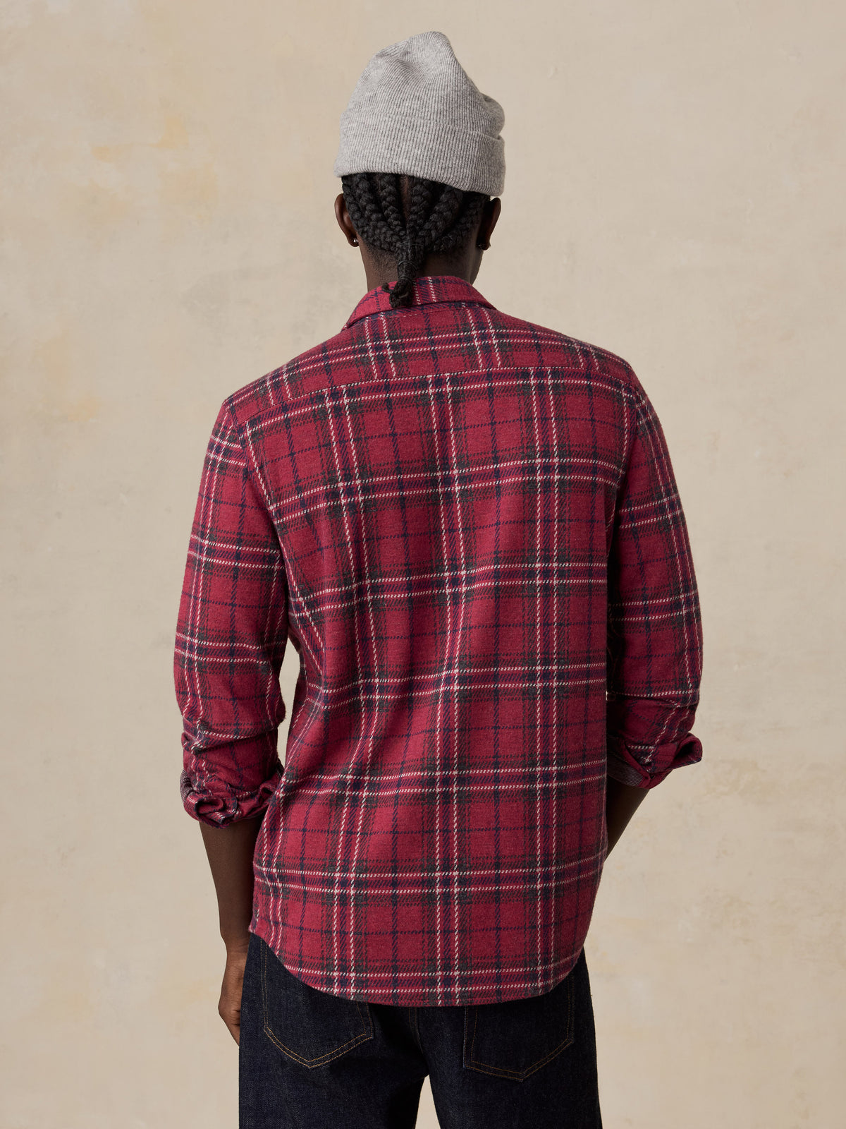 A man viewed from behind wearing a red button up shirt and a grey beanie, image 2 of 6