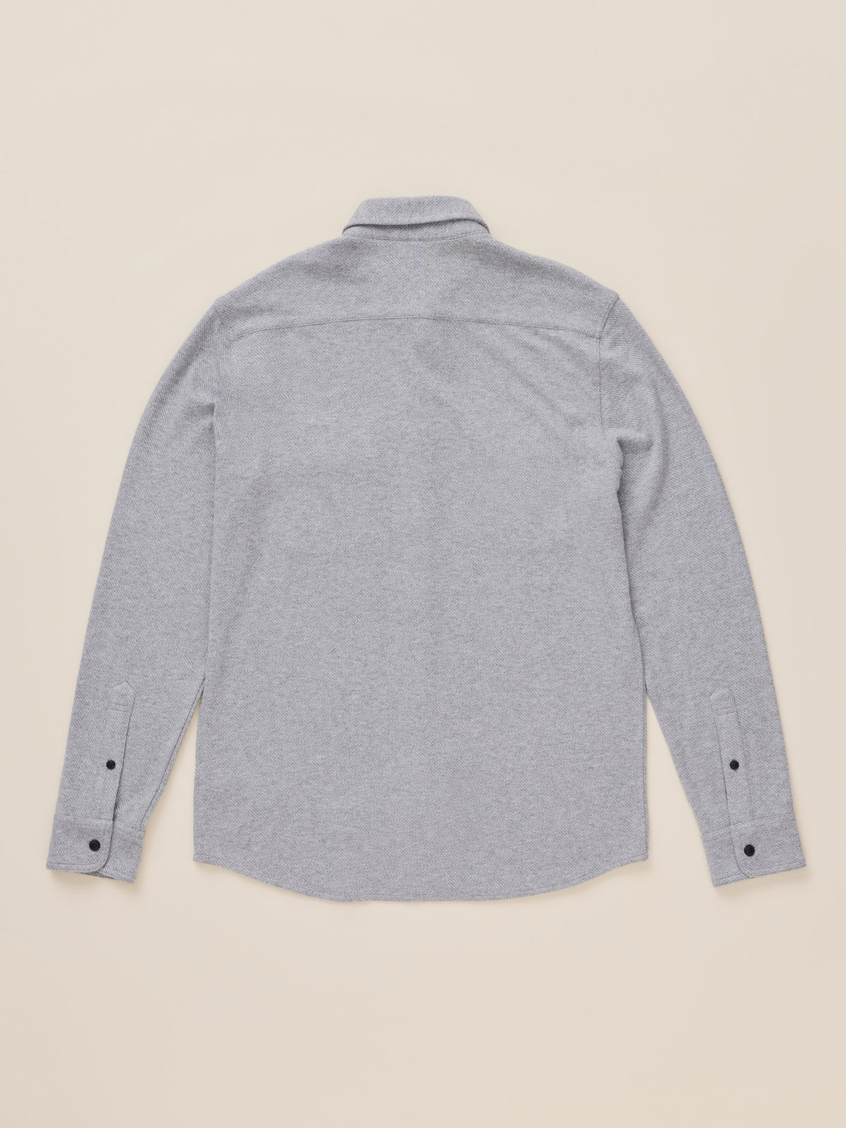 A light gray heather long-sleeve button-up shirt shown from the back, laid flat on a warm beige background., image 8 of 8