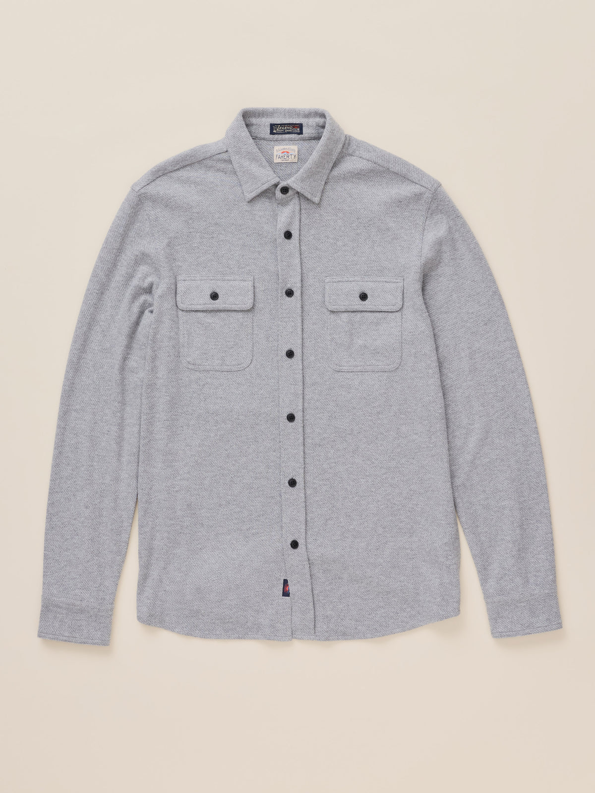 A light gray heather long-sleeve button-up shirt with two buttoned chest flap pockets, laid flat against a solid beige background., image 7 of 8