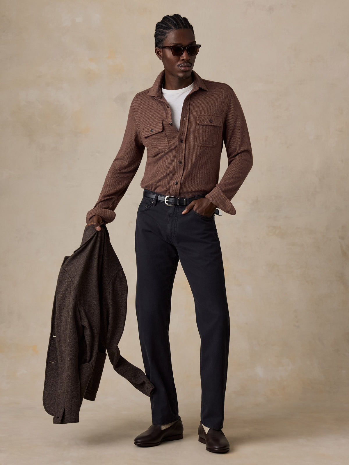 A man wearing a brown shirt and black pants, image 4 of 5
