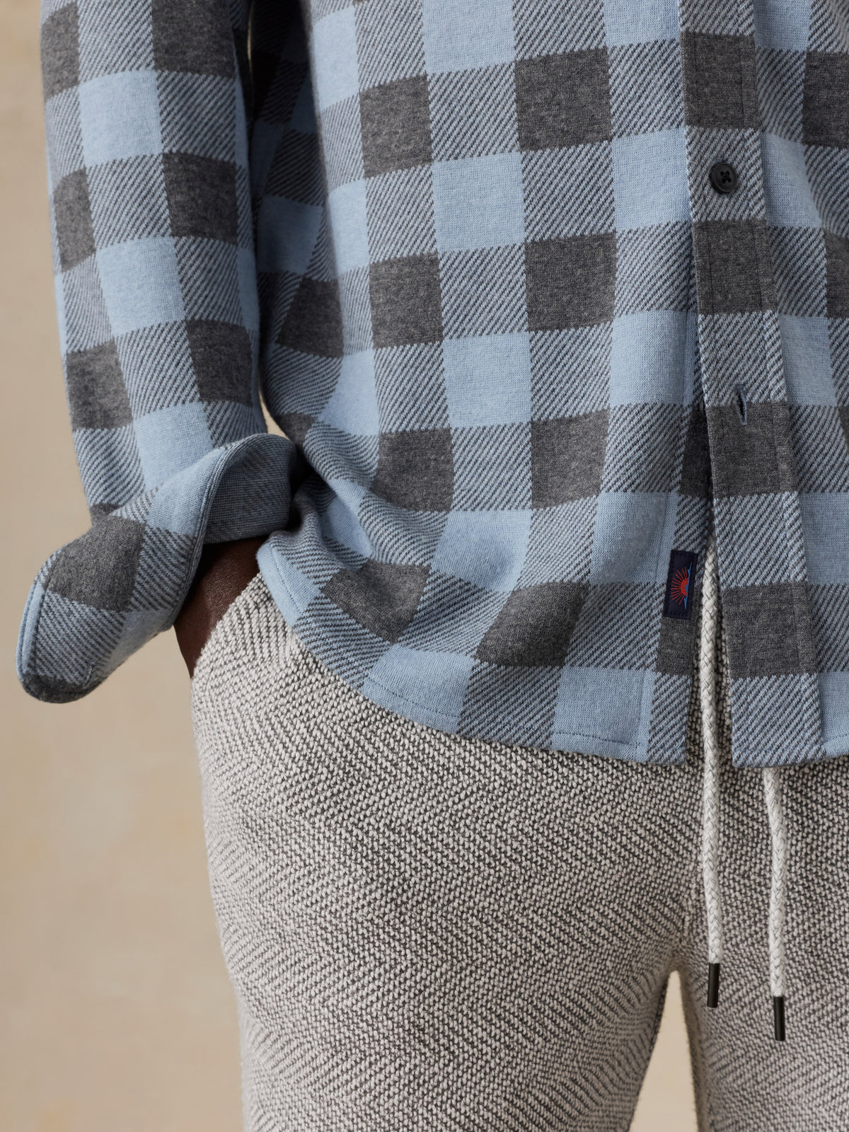 Close up of a man wearing a blue plaid shirt and sweatpants, image 4 of 5