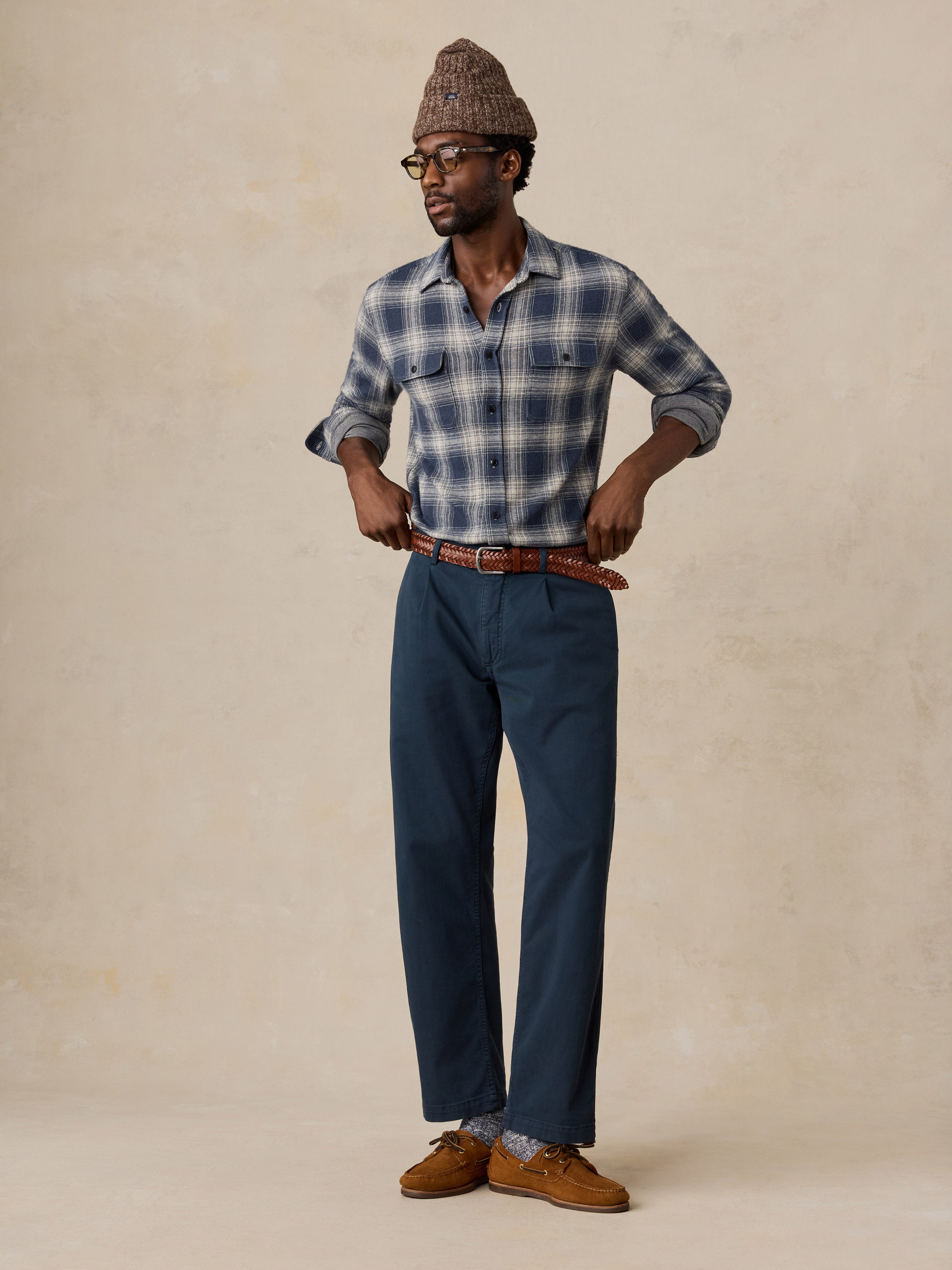 A man wearing a blue button up shirt and navy chino pants