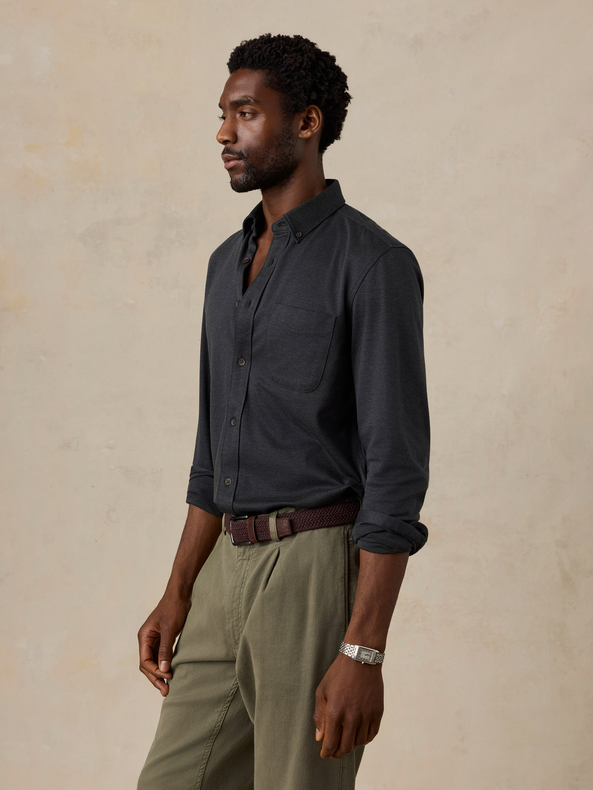 A man wearing a black shirt and green pants, image 4 of 6