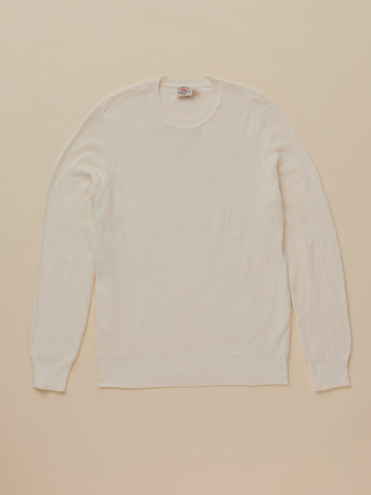A cream-colored long-sleeve crewneck sweater laid flat against a solid beige background., image 6 of 7
