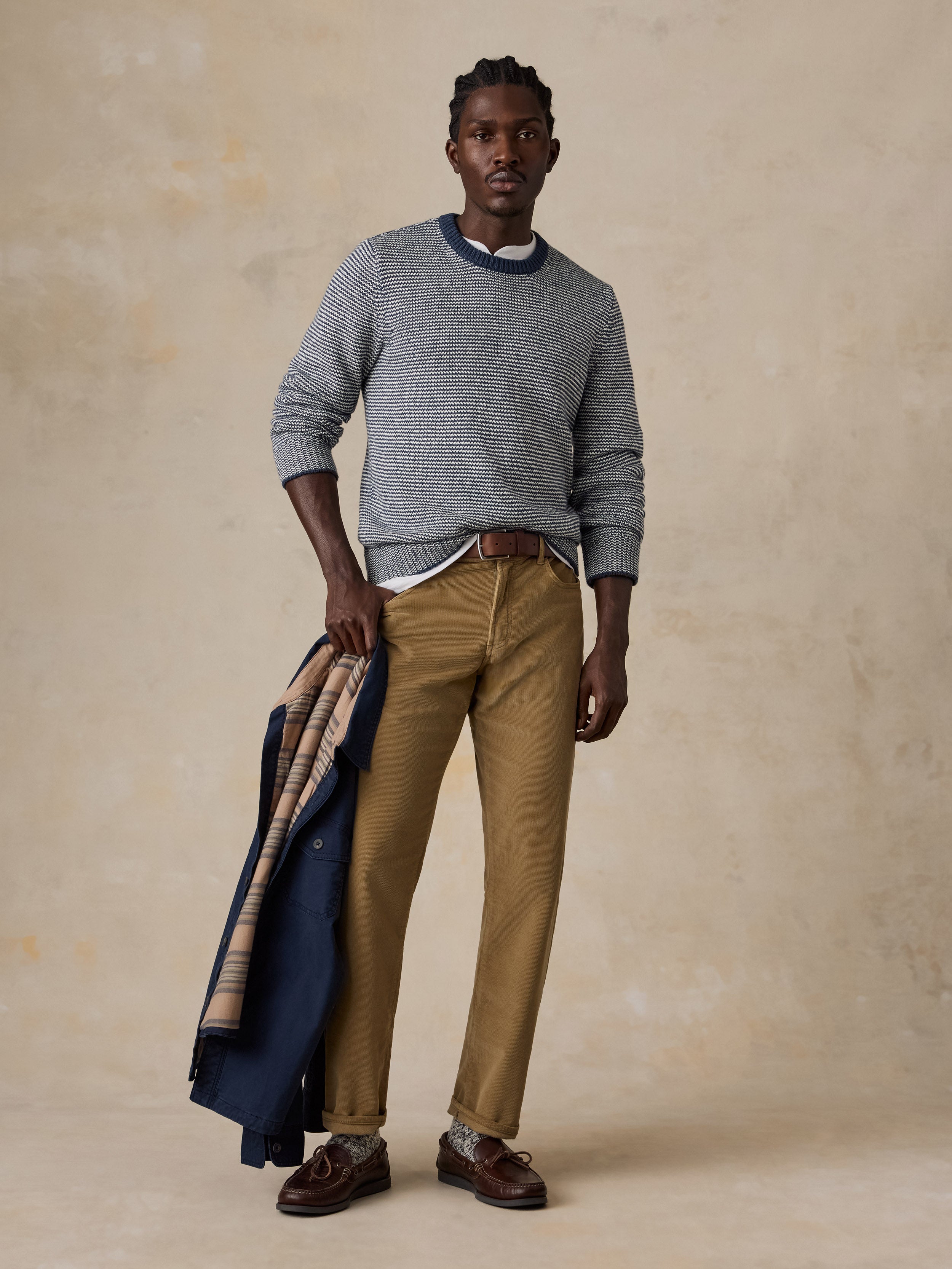 A man wearing a blue striped sweater and tan corduroy pants