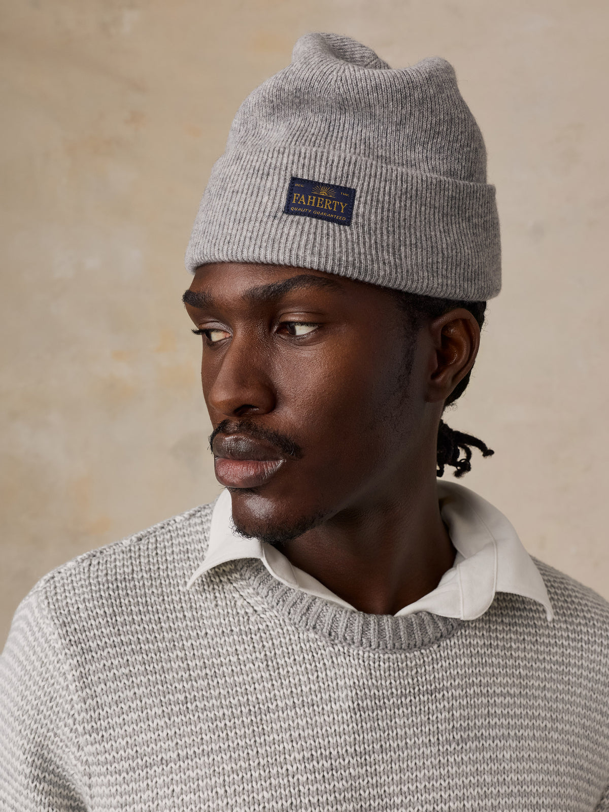 Close up of a man wearing a light grey sweater over a white shirt, image 2 of 5
