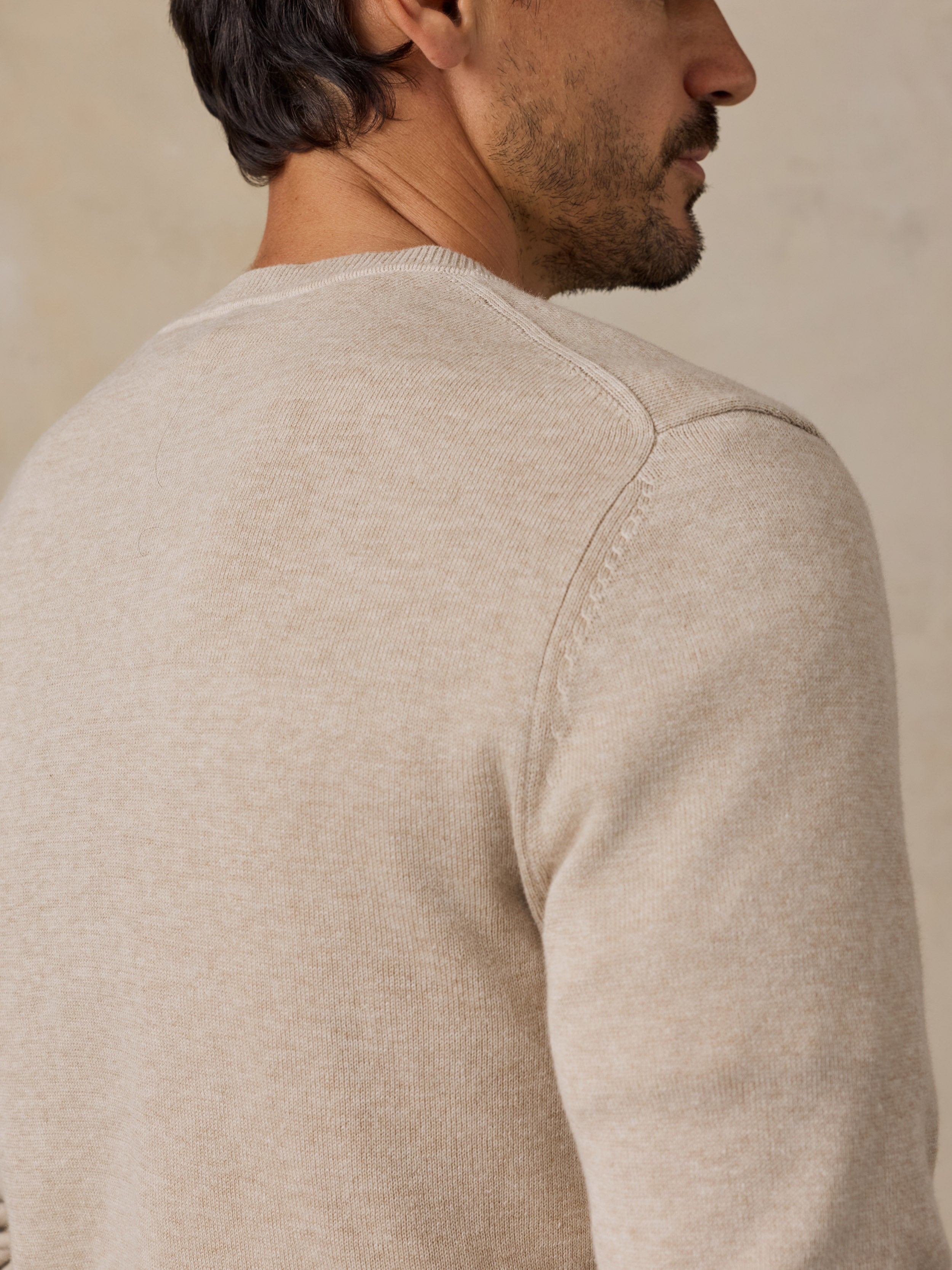 Man wearing a light beige knit crewneck sweater.