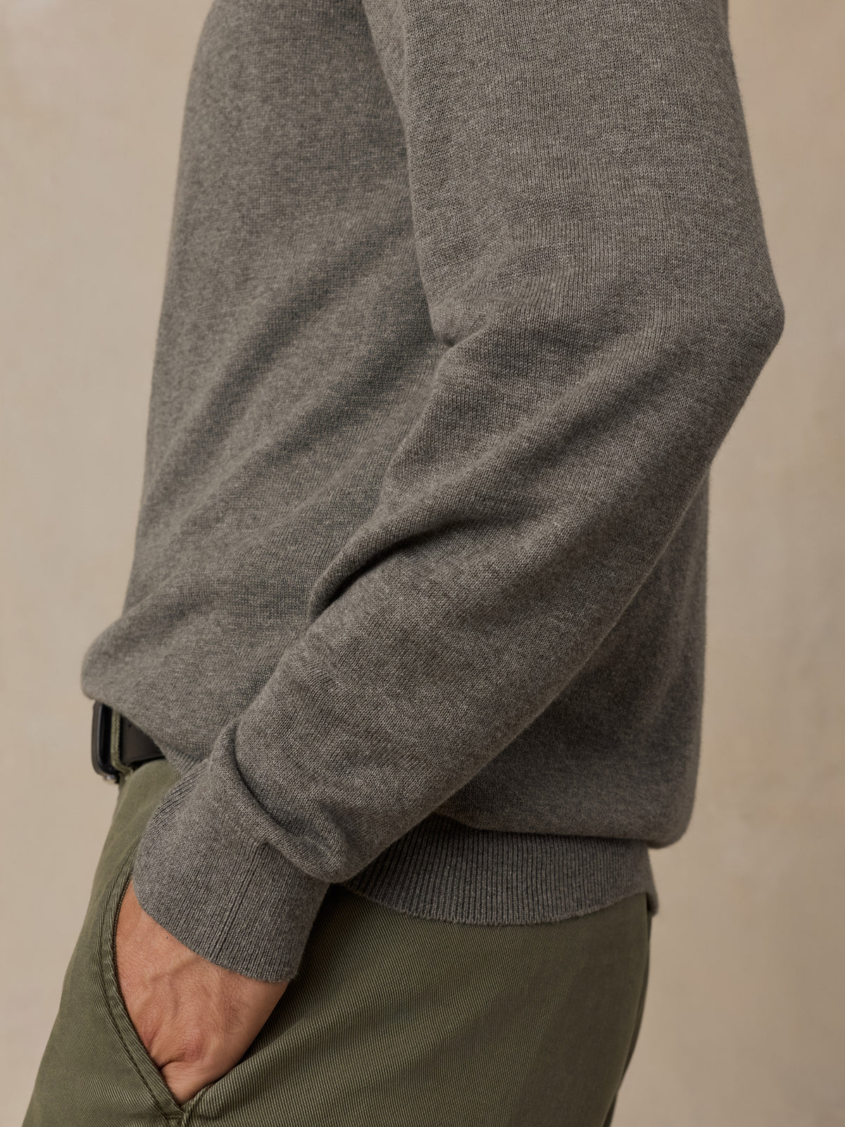 Close-up of a man wearing a green knit sweater and olive green trousers.