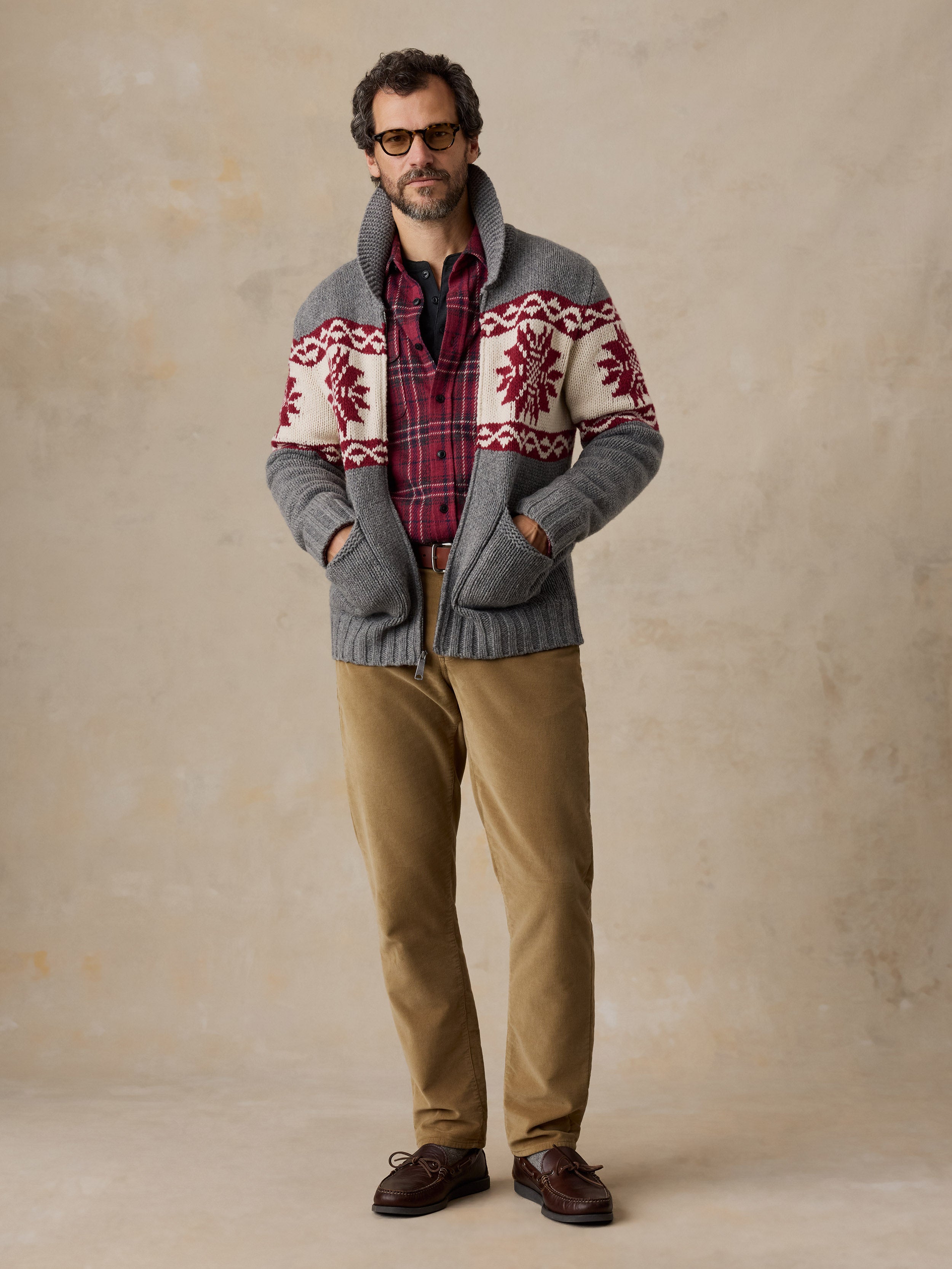 A man wearing a printed wool cardigan and tan pants