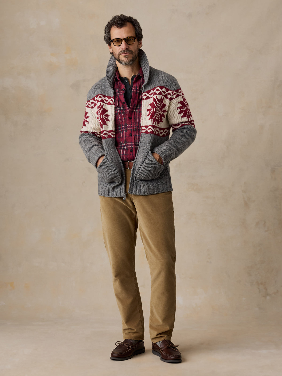 A man wearing a printed wool cardigan and tan pants, image 1 of 5