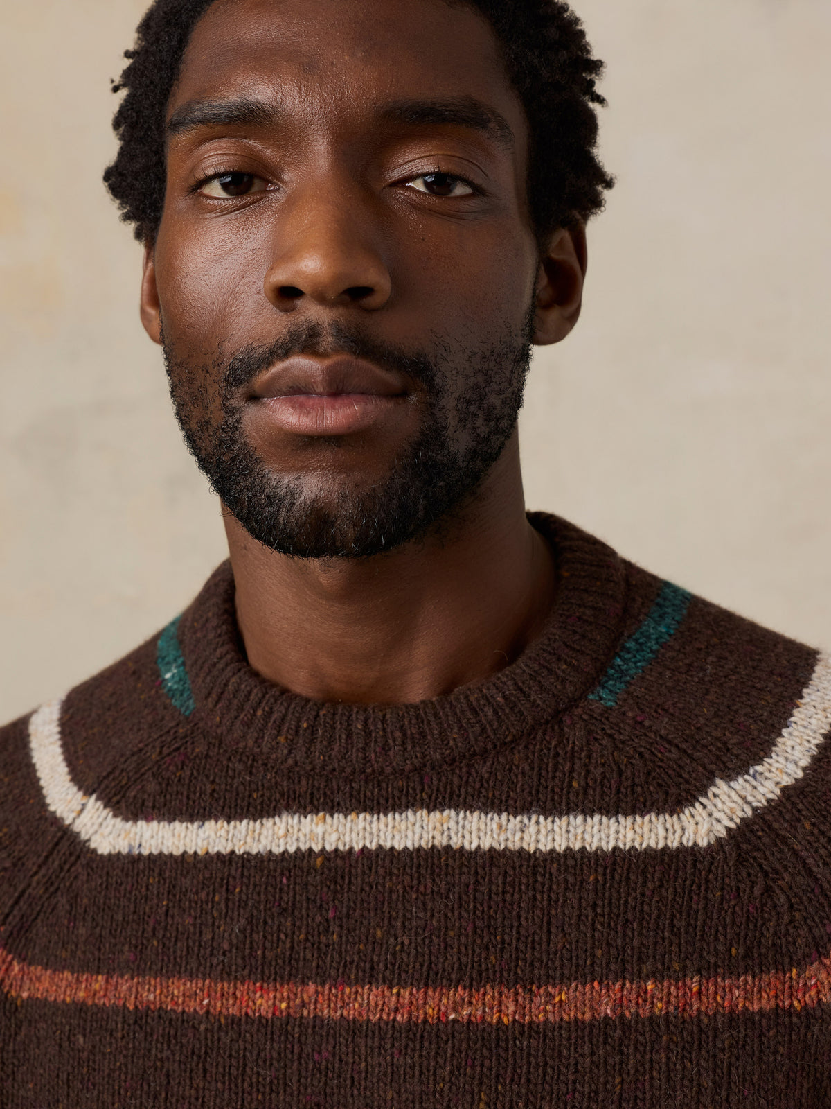 Close up of a man wearing a brown striped sweater, image 4 of 6