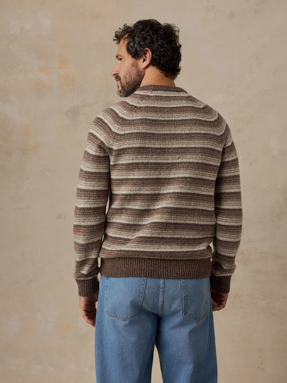 A man viewed from behind wearing a brown striped sweater, image 3 of 5