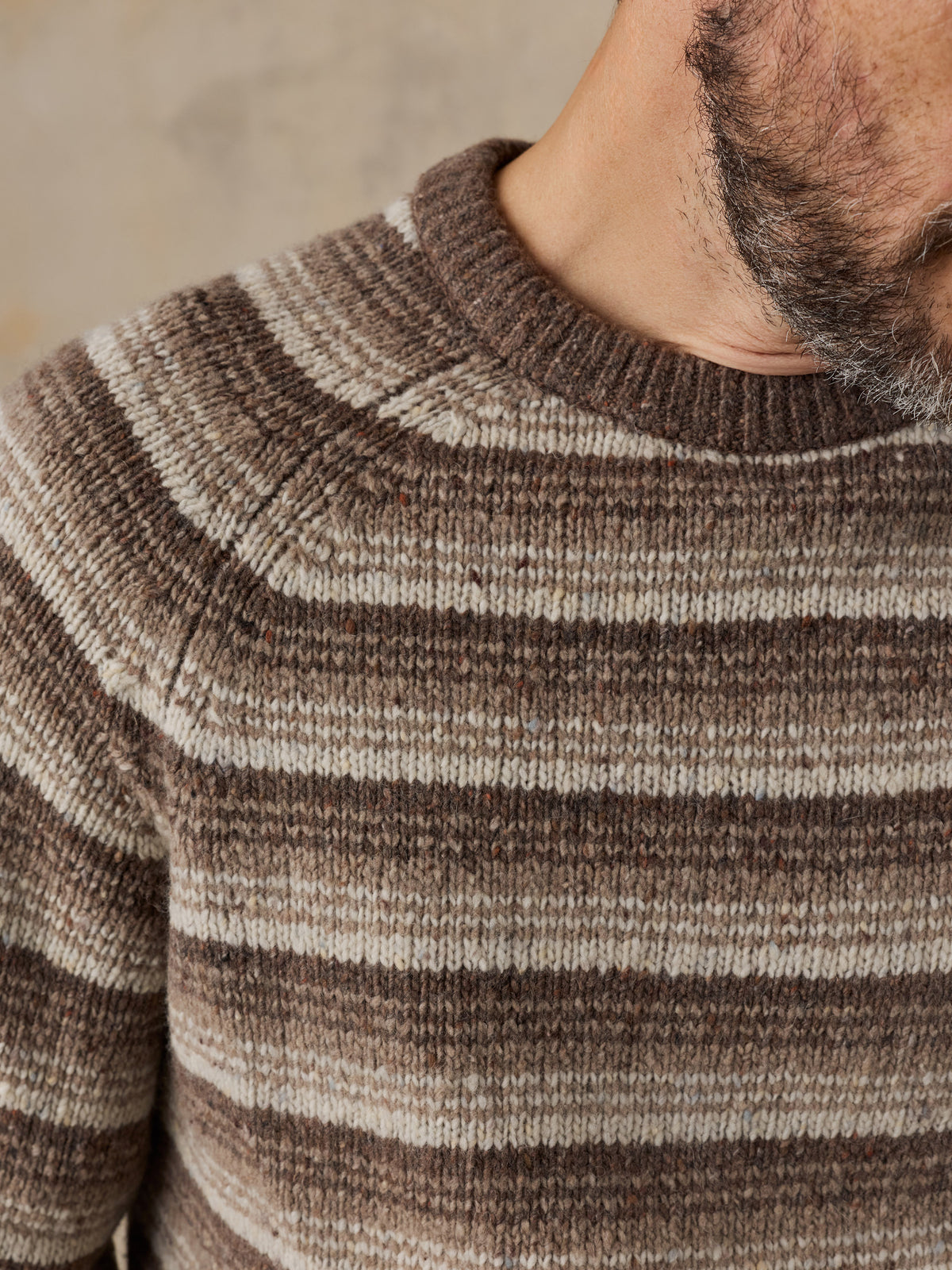 Close up of a man wearing a brown striped sweater, image 4 of 5