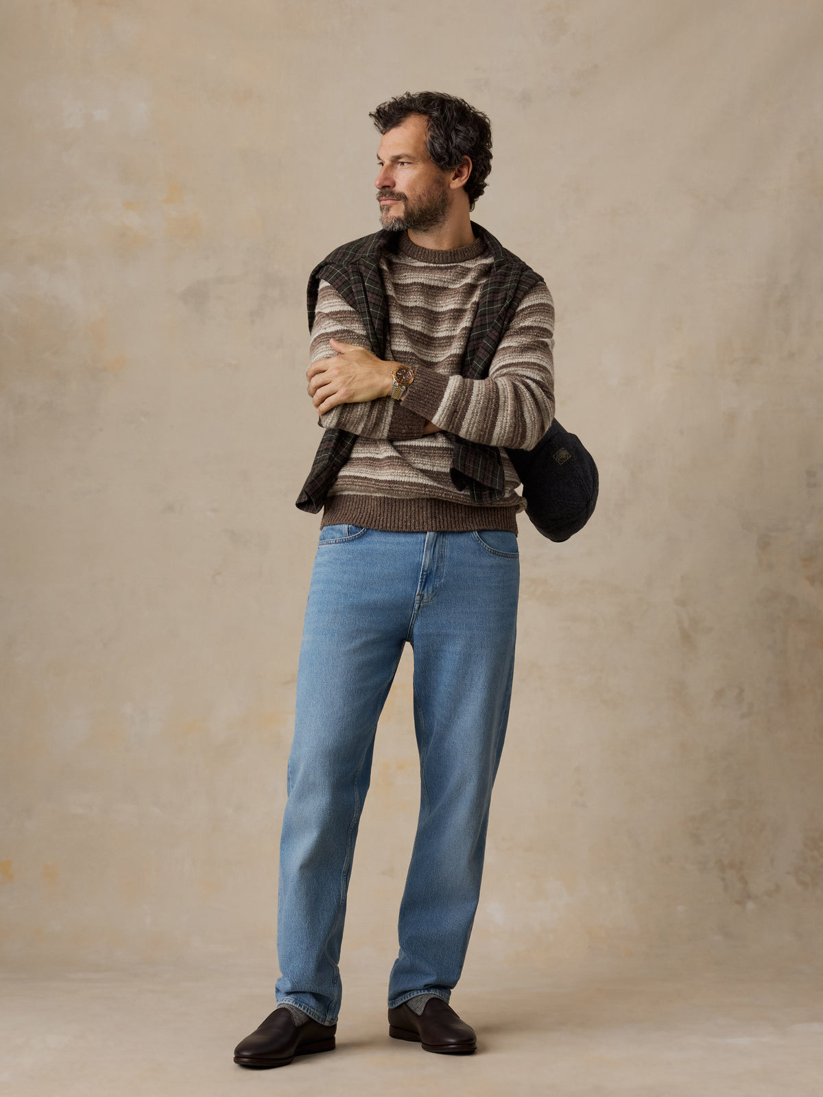 A man wearing a brown striped sweater and jeans, image 2 of 5