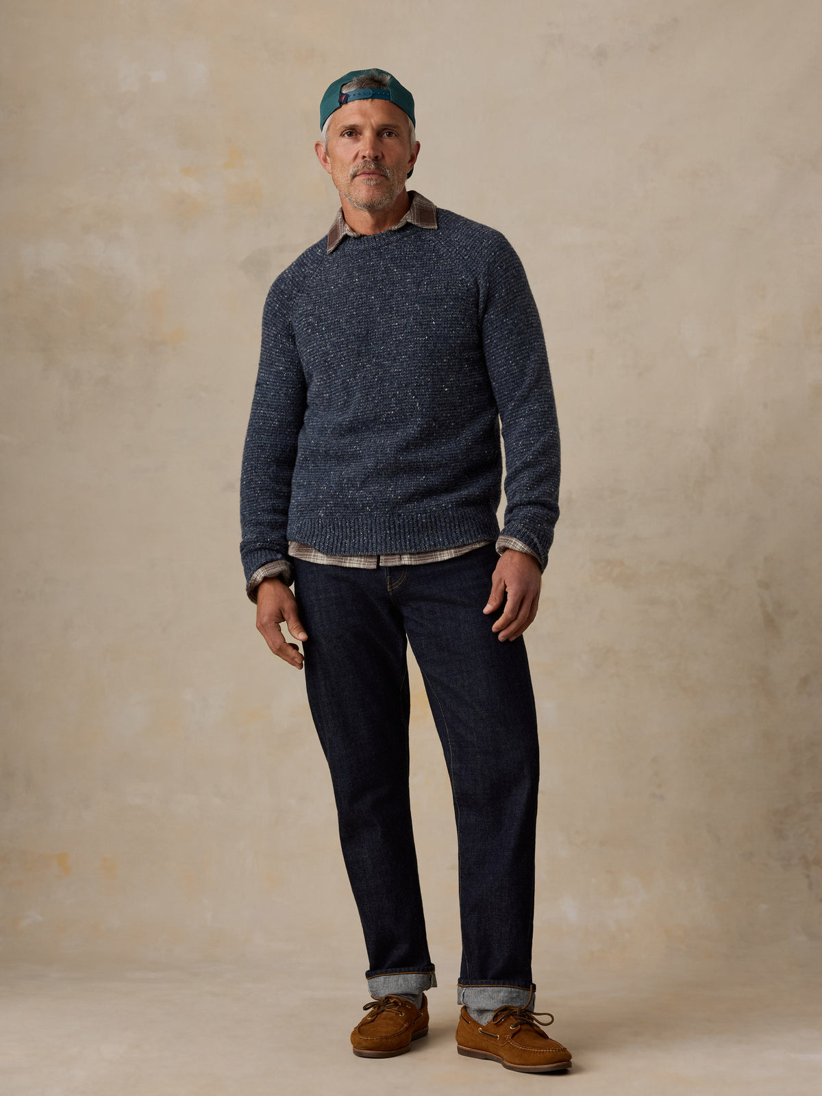 A man wearing a blue sweater and jeans, image 2 of 5
