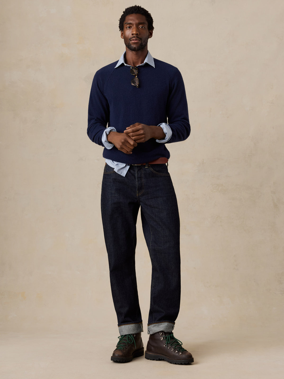 A man wearing a blue crewneck and jeans, image 2 of 7