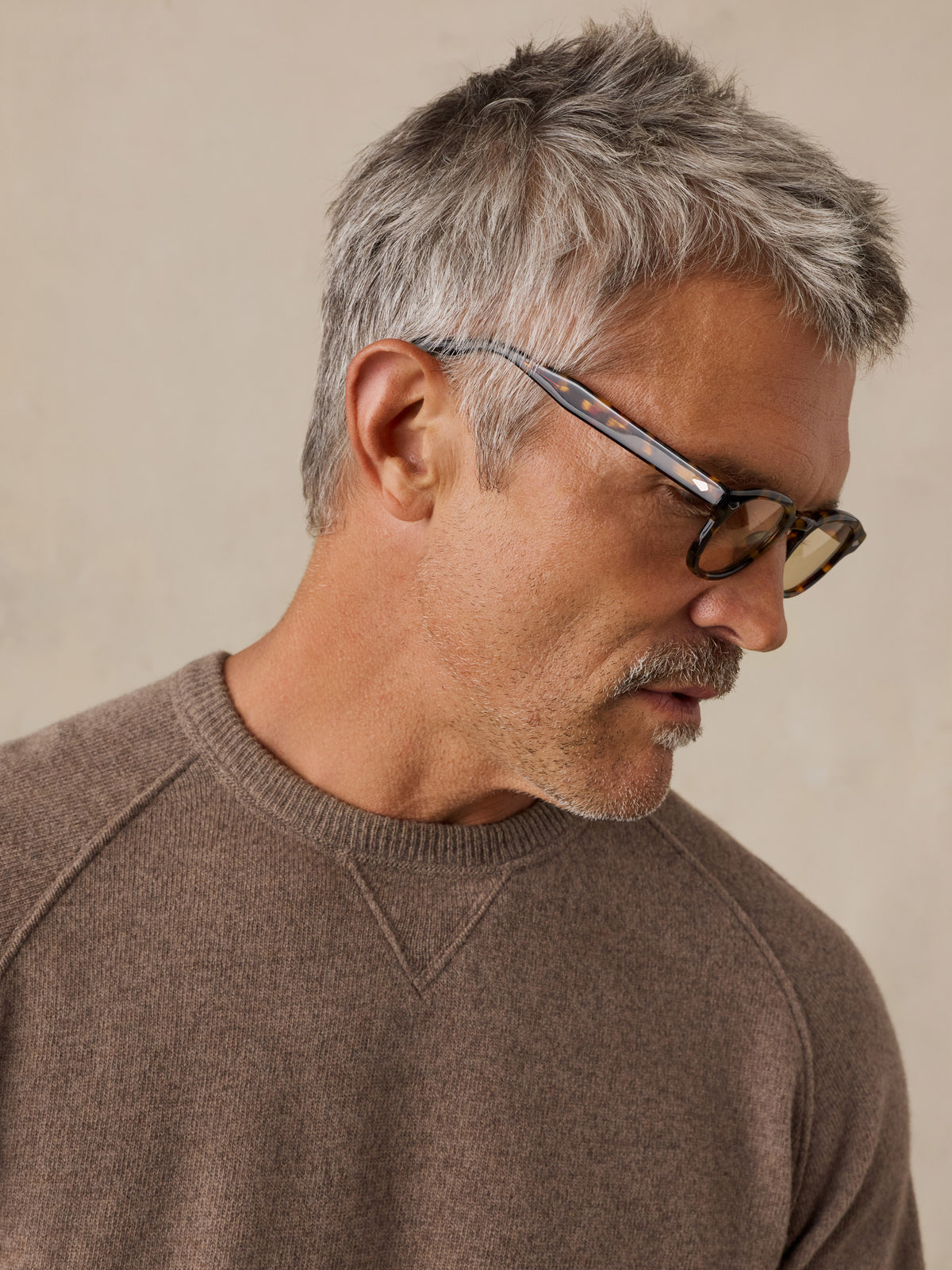 Close up of a man wearing a brown sweater and sunglasses, image 3 of 5