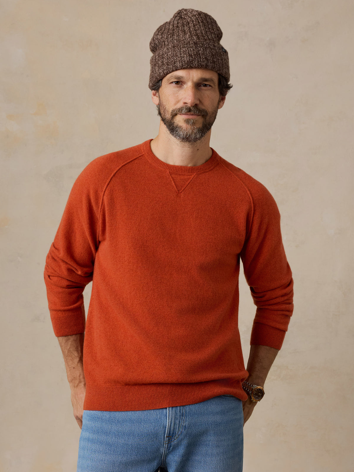 A man wearing an orange sweater and a beanie, image 1 of 6