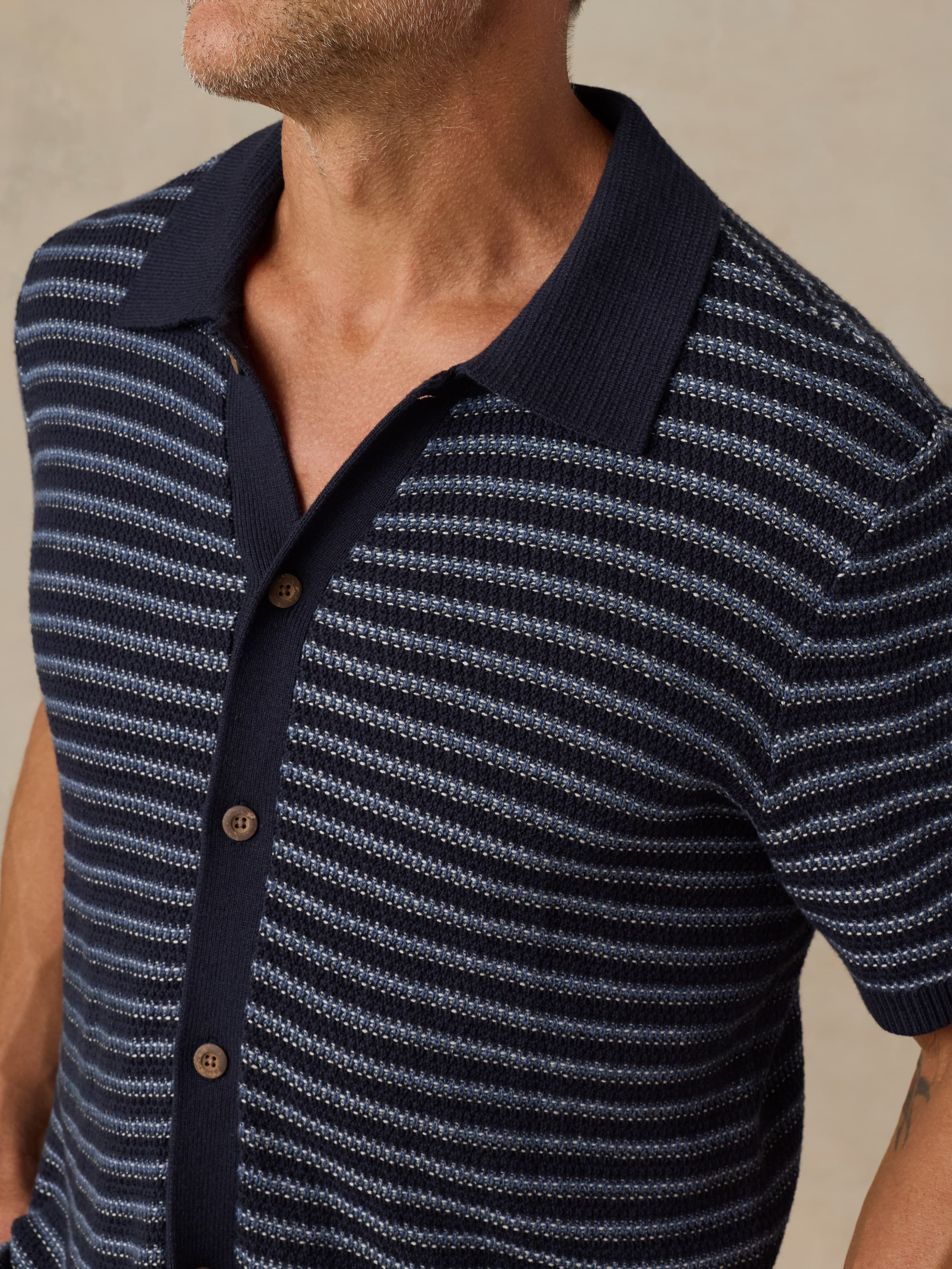 Man wearing a navy and white striped short-sleeve shirt with a collar.