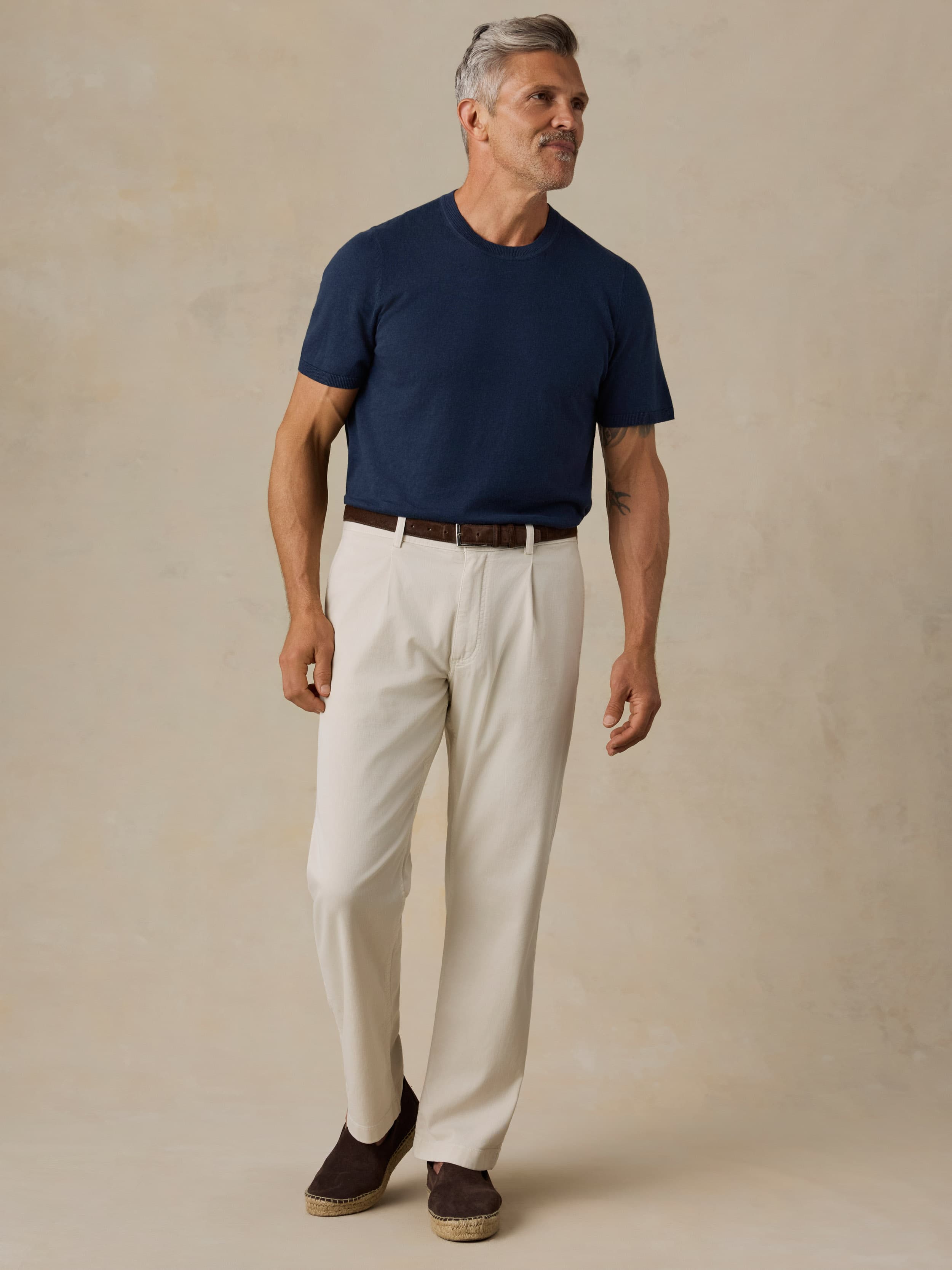 Man wearing a navy shirt and beige pants against a beige background