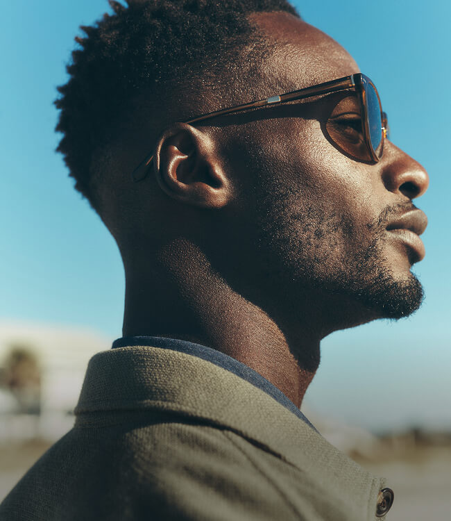 close up of male model wearing brown sunglasses paired with a linen jacket