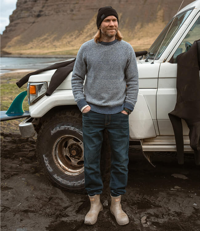 Man standing next to a range rover in the Icelandic coast wearing a sweater and stretch terry pants
