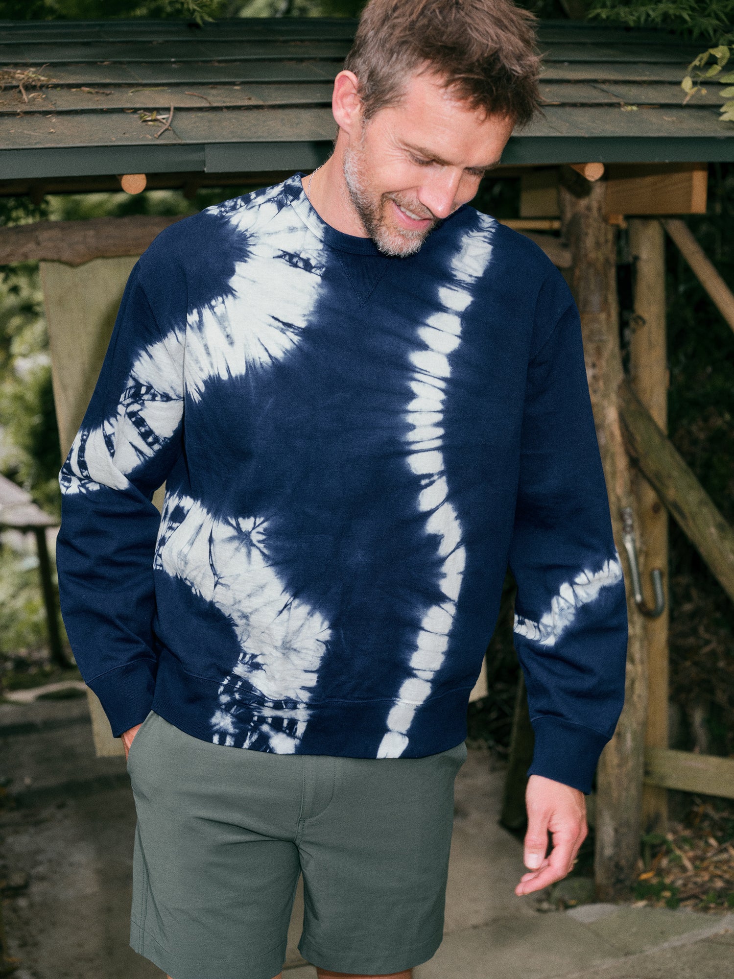 Man wearing a blue tie dye sweatshirt and green shorts