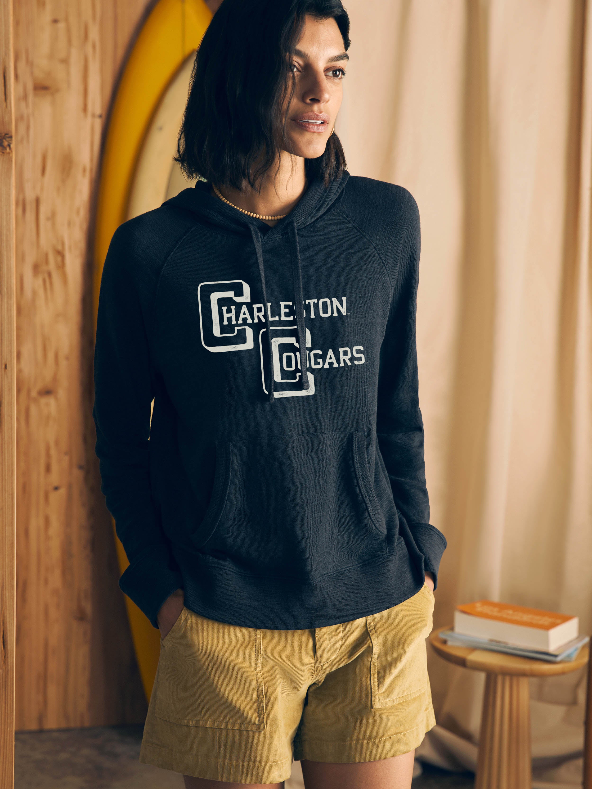 Woman wearing a navy hoodie with College of Charleston graphic at the center chest