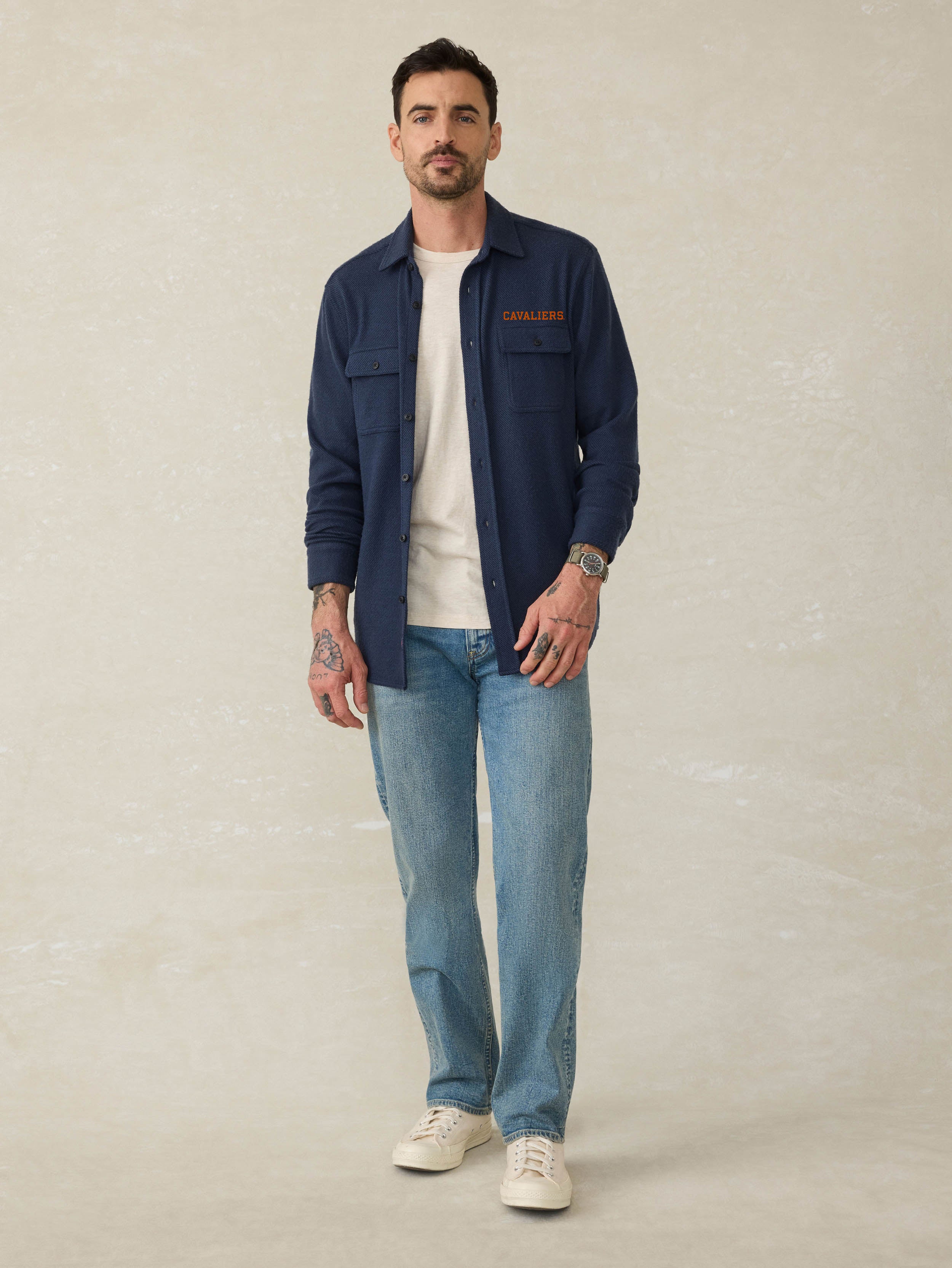 Man wearing a navy blue shirt with University of Virginia graphic against a beige background