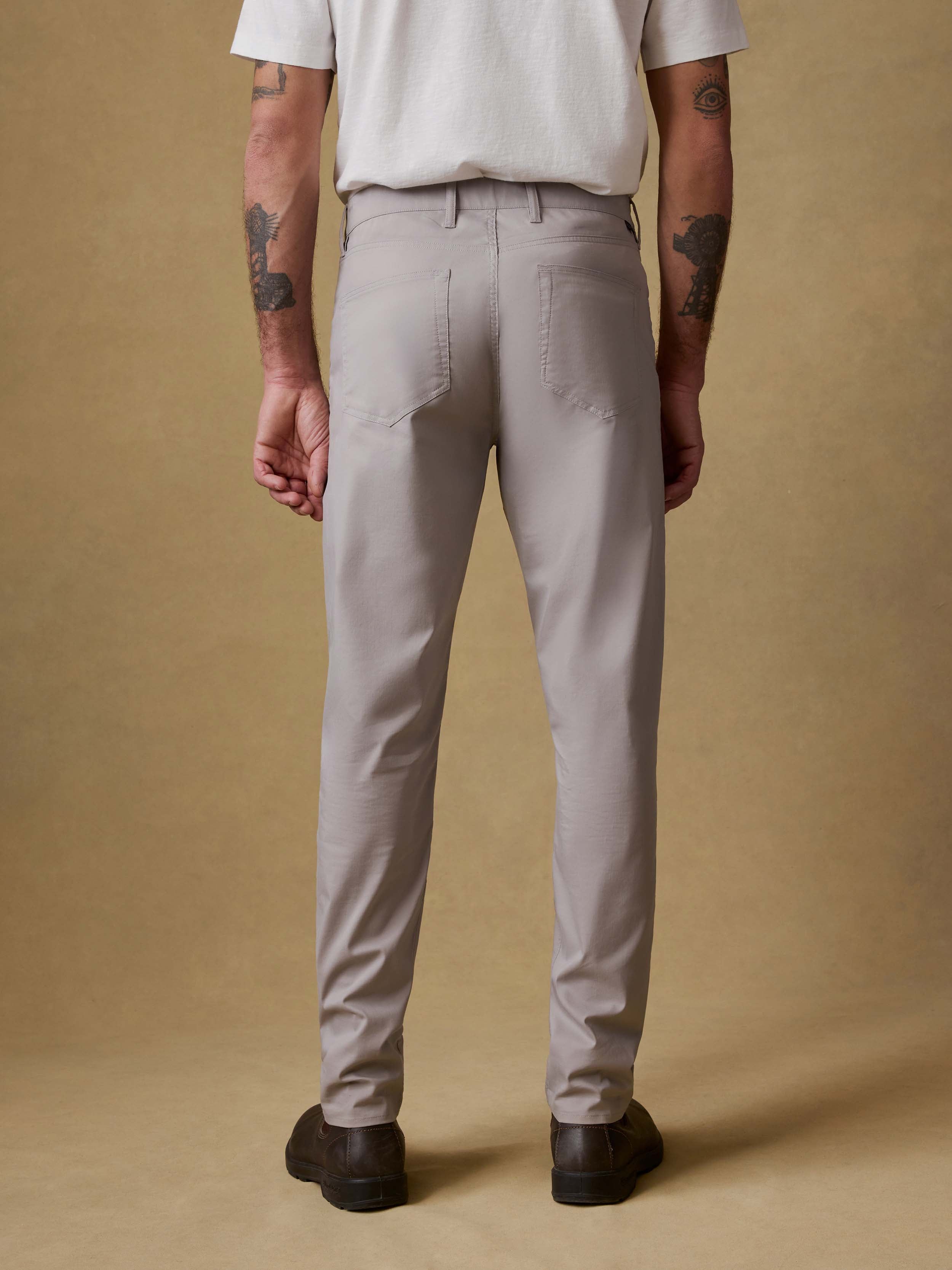 Back view of a man wearing light gray pants on a beige background