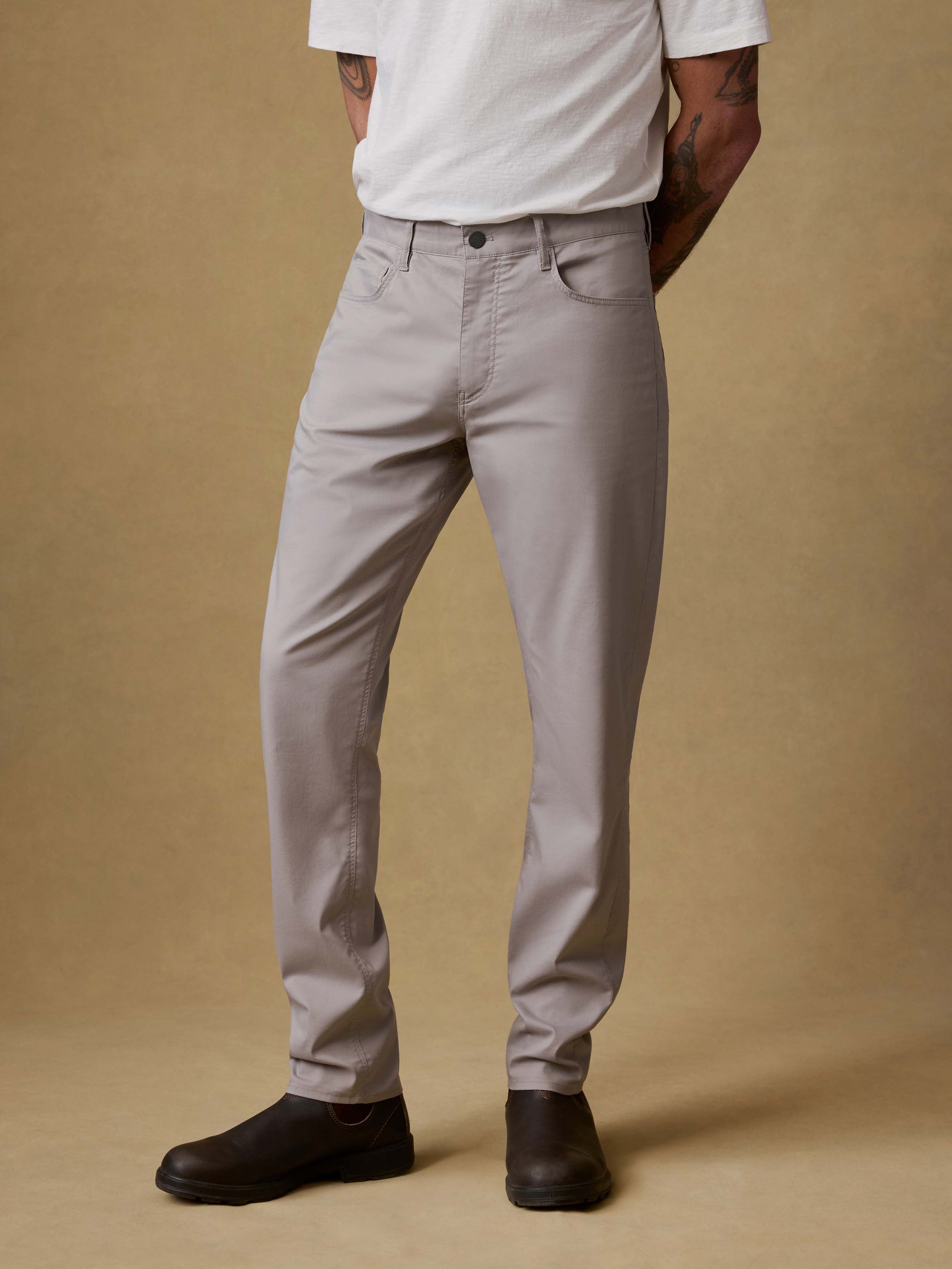 Man wearing light gray pants and a white shirt on a beige background