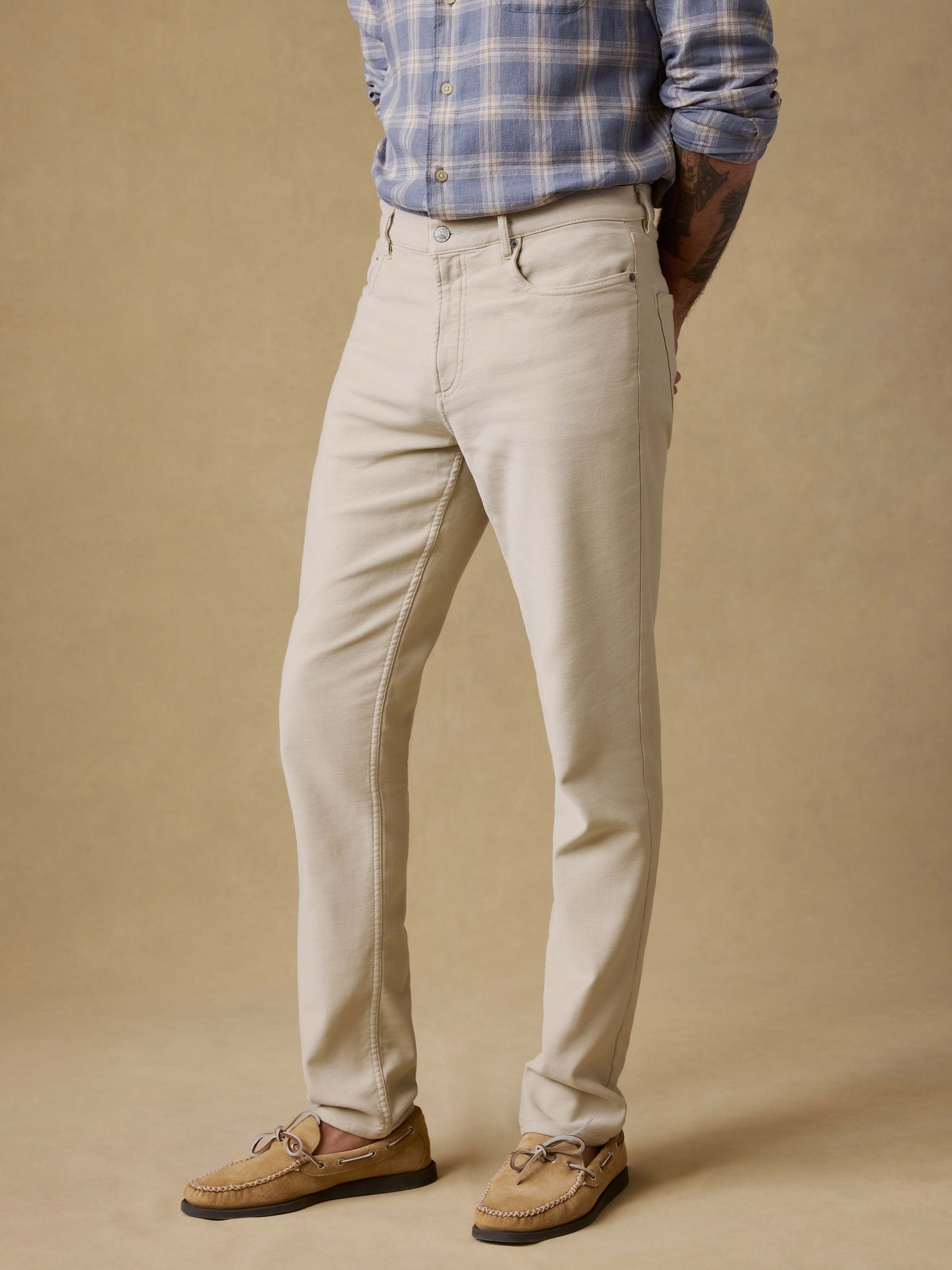 Man wearing a blue plaid shirt and beige pants against a beige background