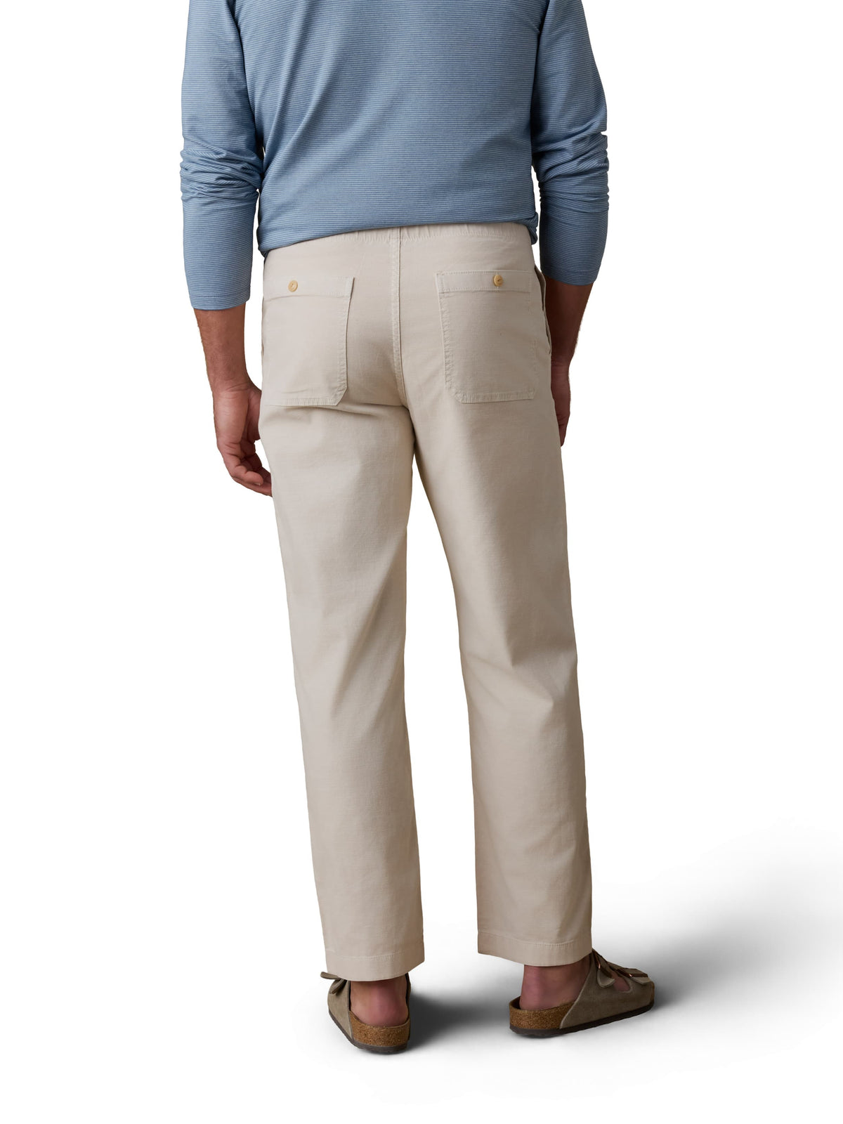 A man viewed from behind wearing a blue polo, beige pants, and birkenstocks, image 3 of 3
