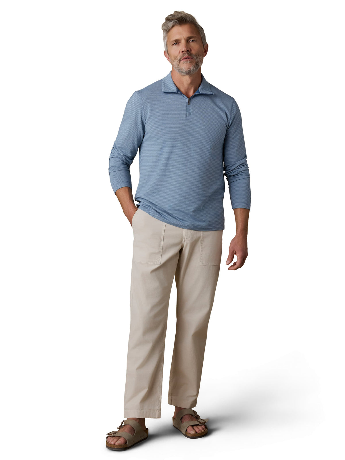 A man wearing a blue polo, beige pants, and birkenstocks, image 1 of 3