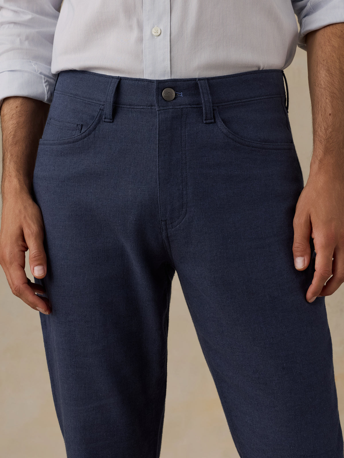 Man wearing a blue checkered shirt and navy pants on a beige background, image 5 of 5