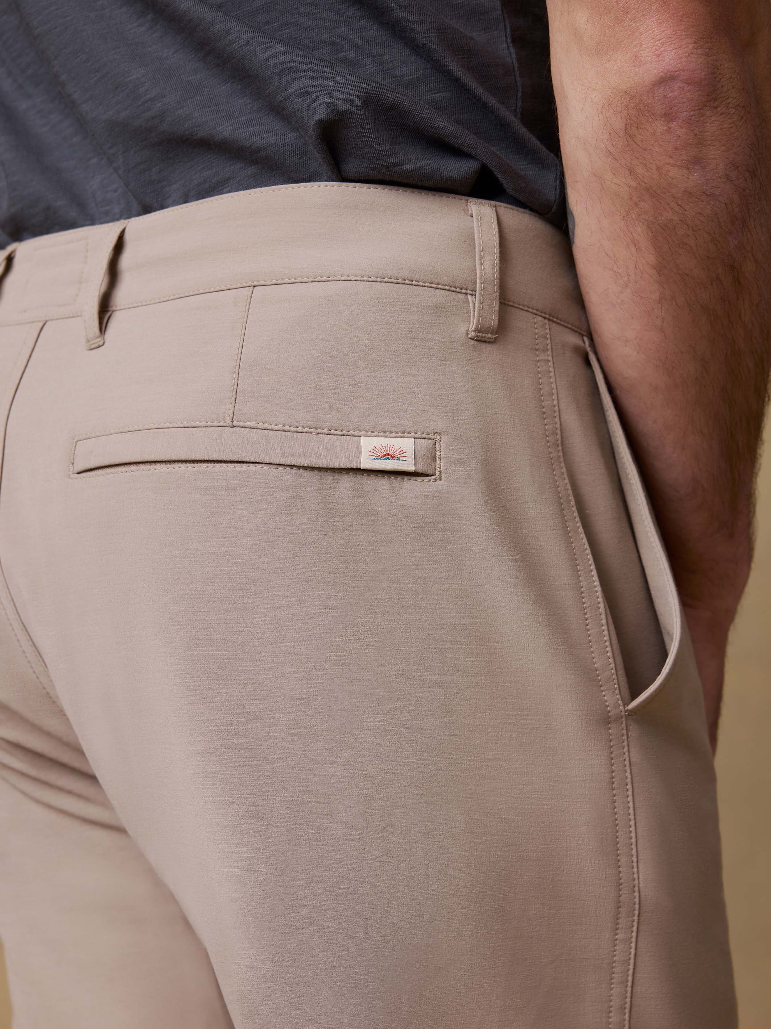 Detail back view of a man wearing a dark gray t-shirt and beige shorts against a beige background