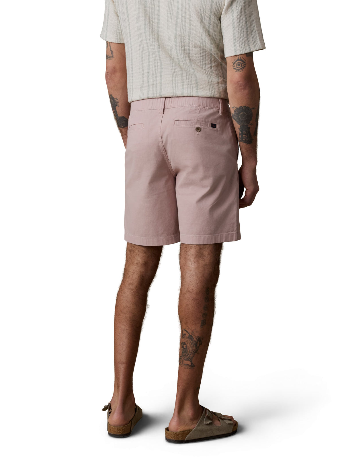 A man viewed from behind wearing a white striped button up shirt, pink pants, and birkenstocks, image 3 of 4
