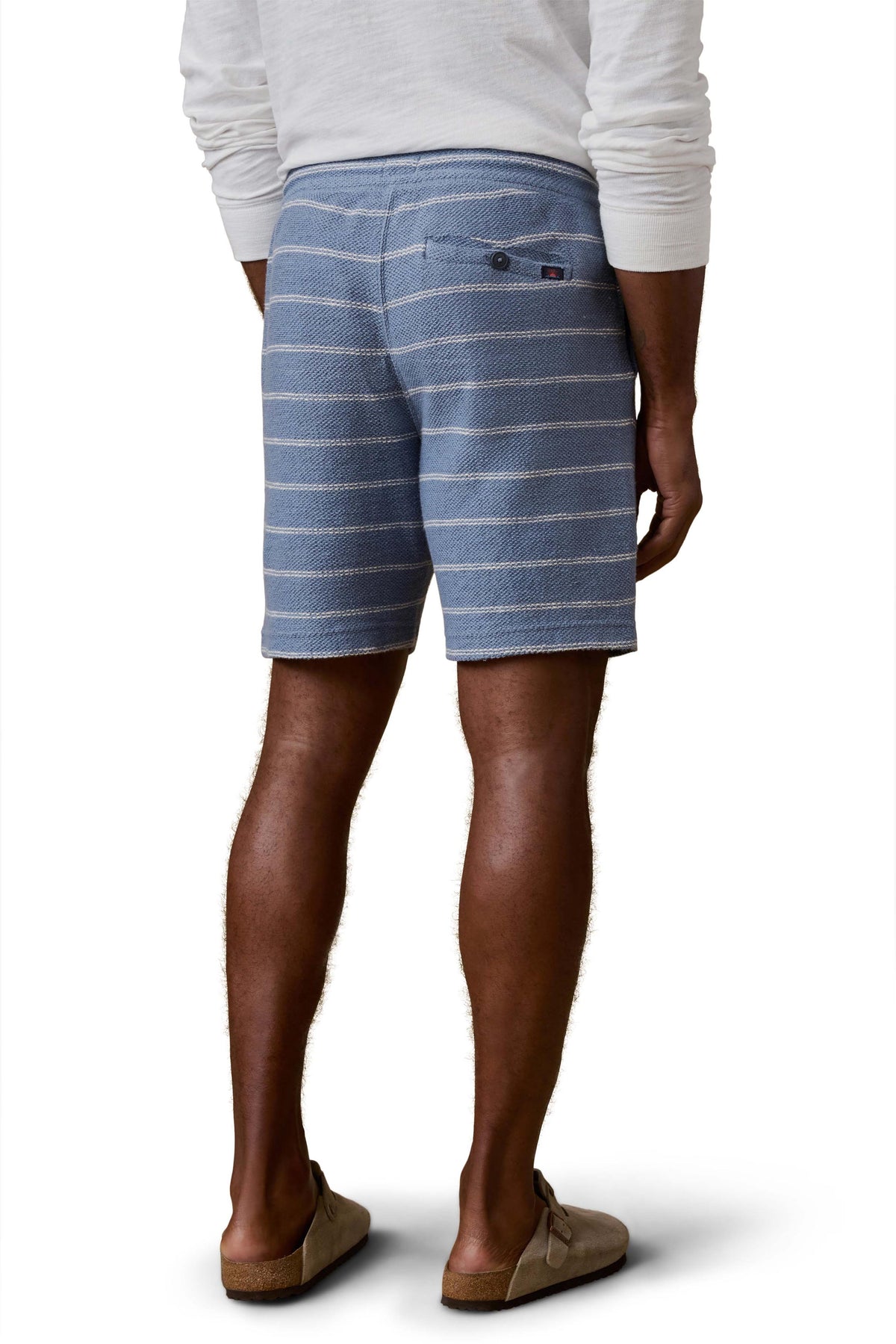 A man viewed from behind wearing blue and white striped shorts and white shirt, image 3 of 3