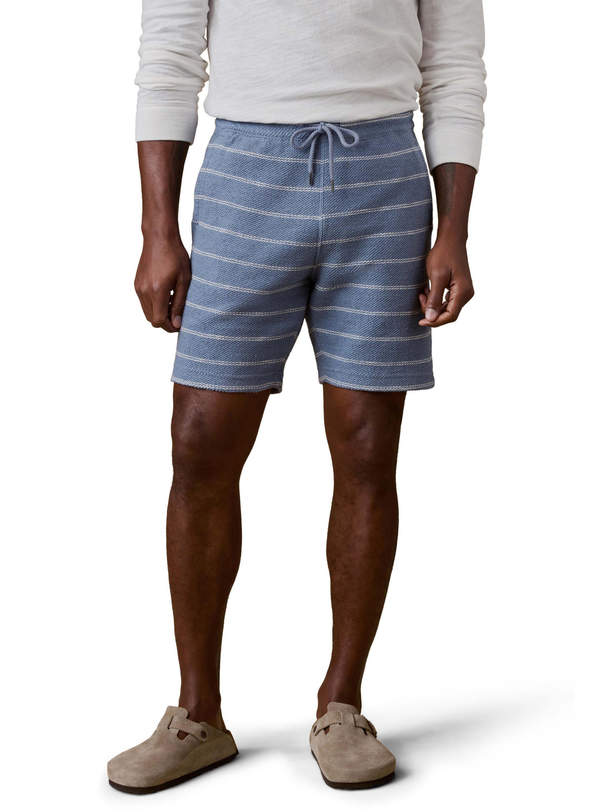 A man wearing blue and white striped shorts and white shirt, image 2 of 3