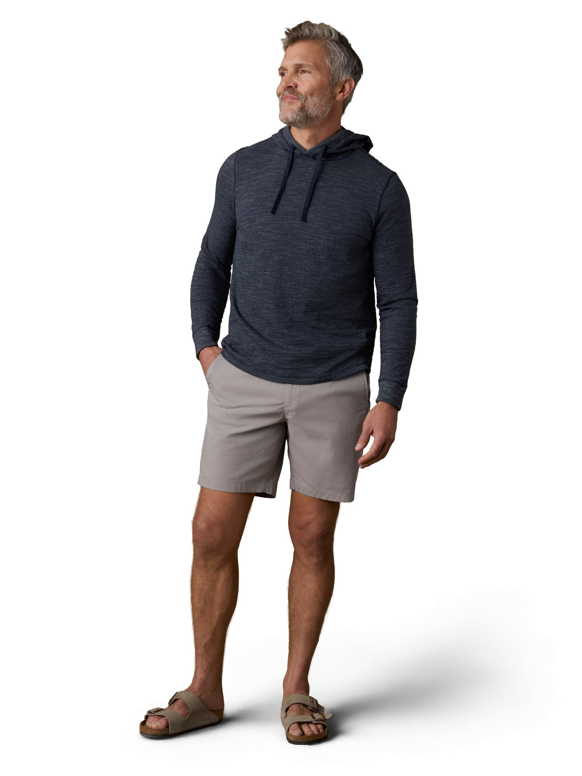 A man wearing a blue hoodie, grey shorts, and birkenstocks, image 1 of 3