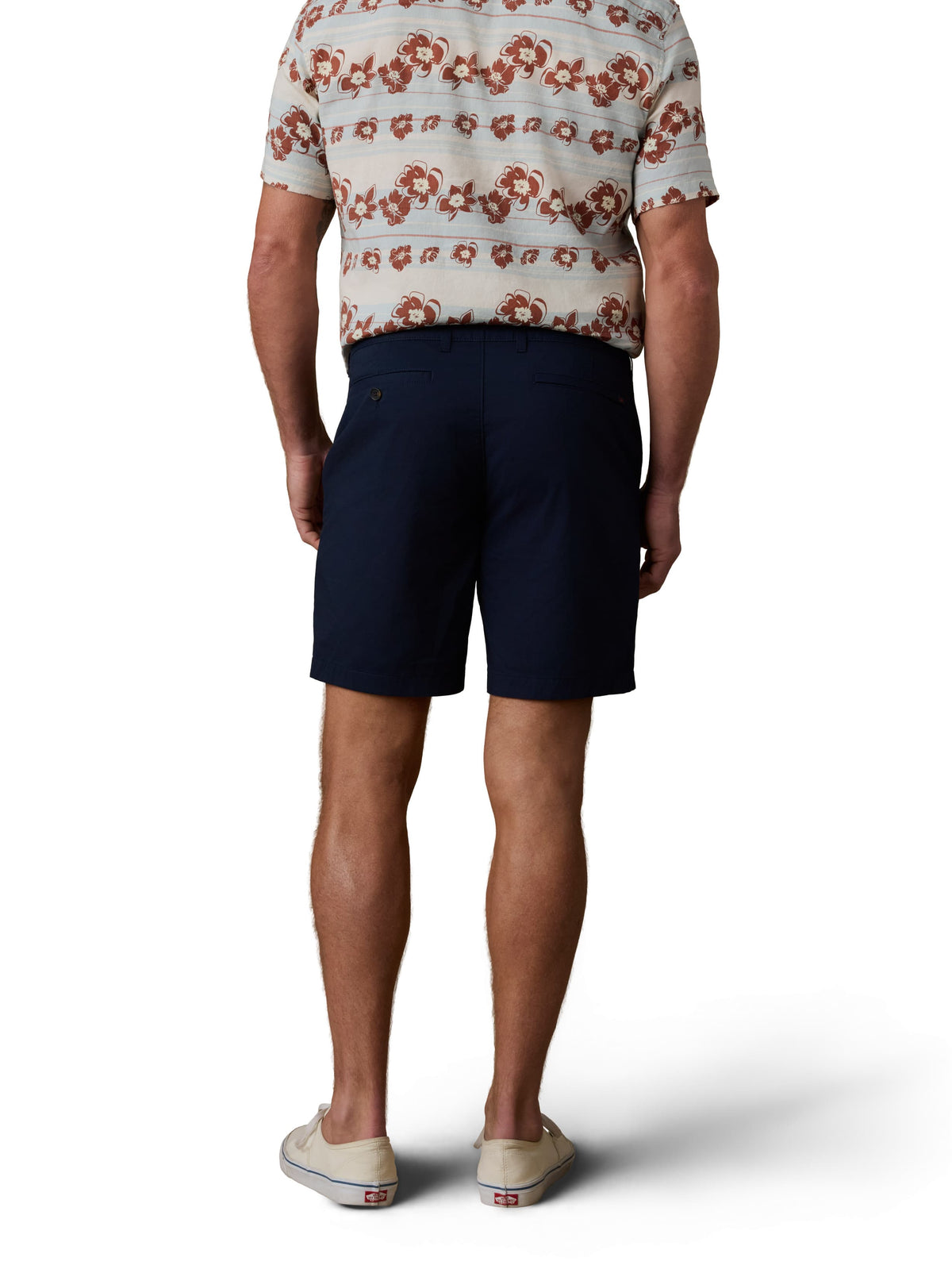 A man viewed from behind wearing a printed button up shirt, navy shorts, and white sneakers, image 3 of 3