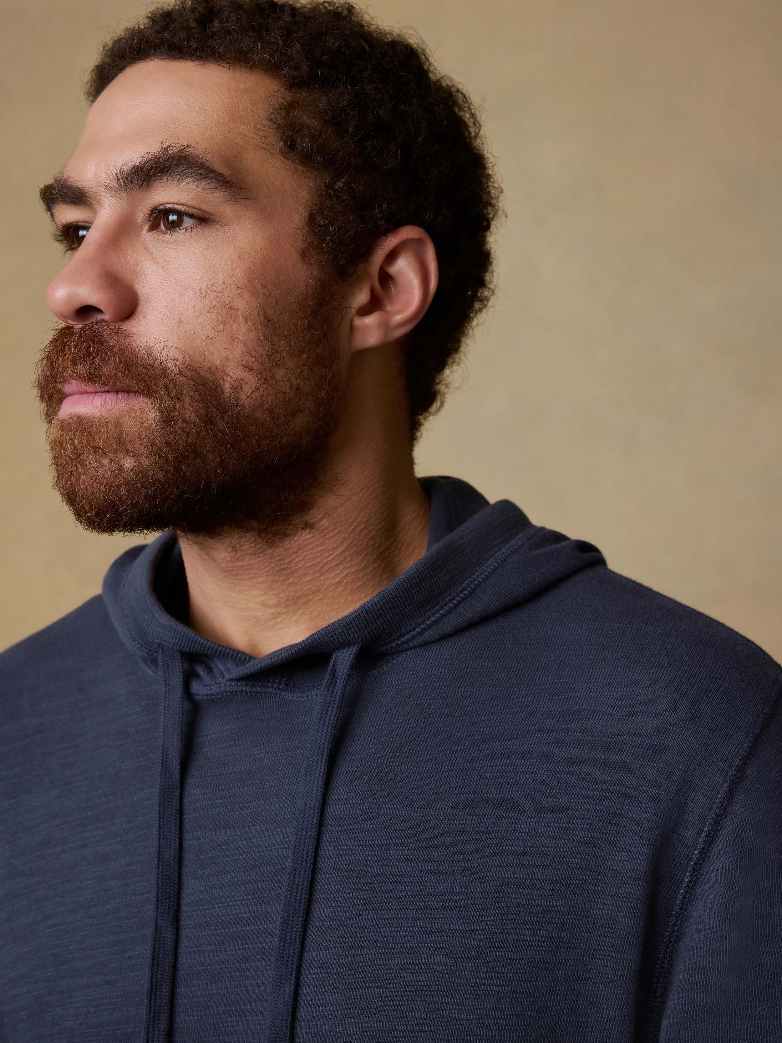 Man wearing a navy blue hoodie against a beige background