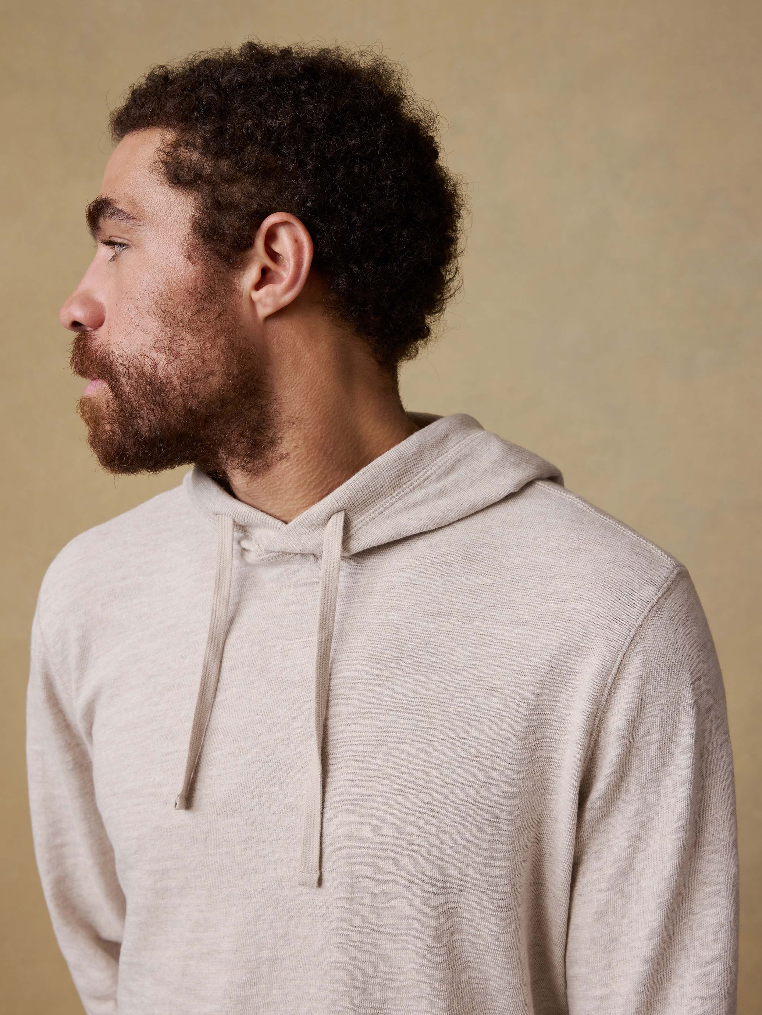 Man wearing a beige hoodie against a beige background