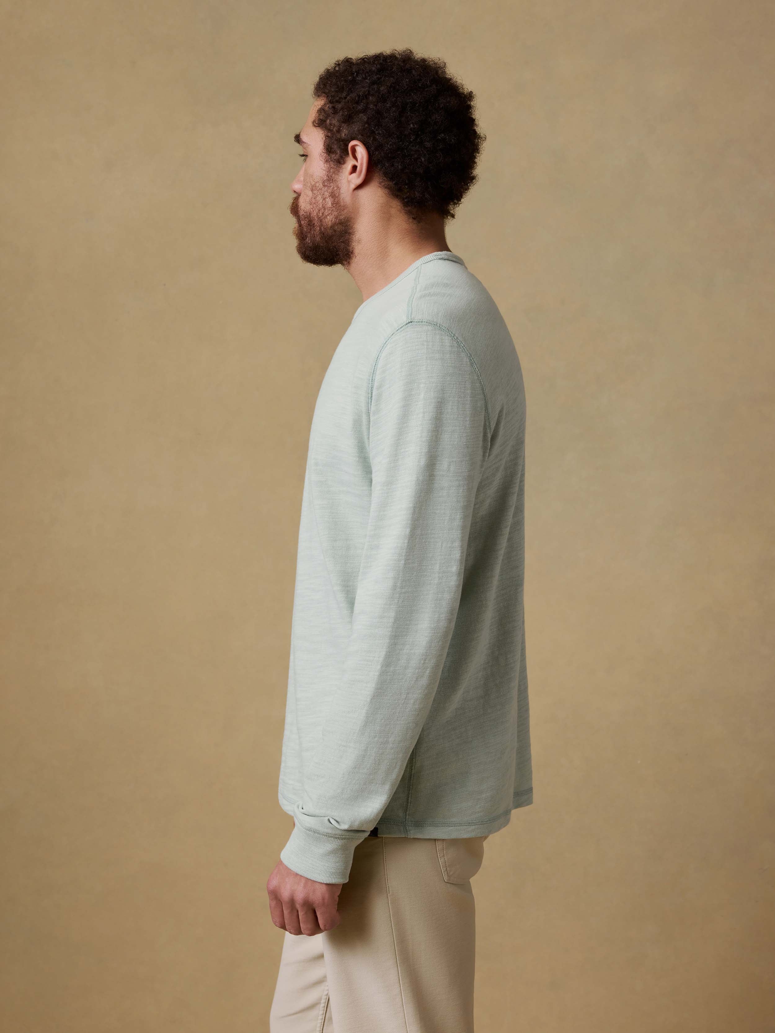 Man wearing a light green long-sleeve shirt against a beige background