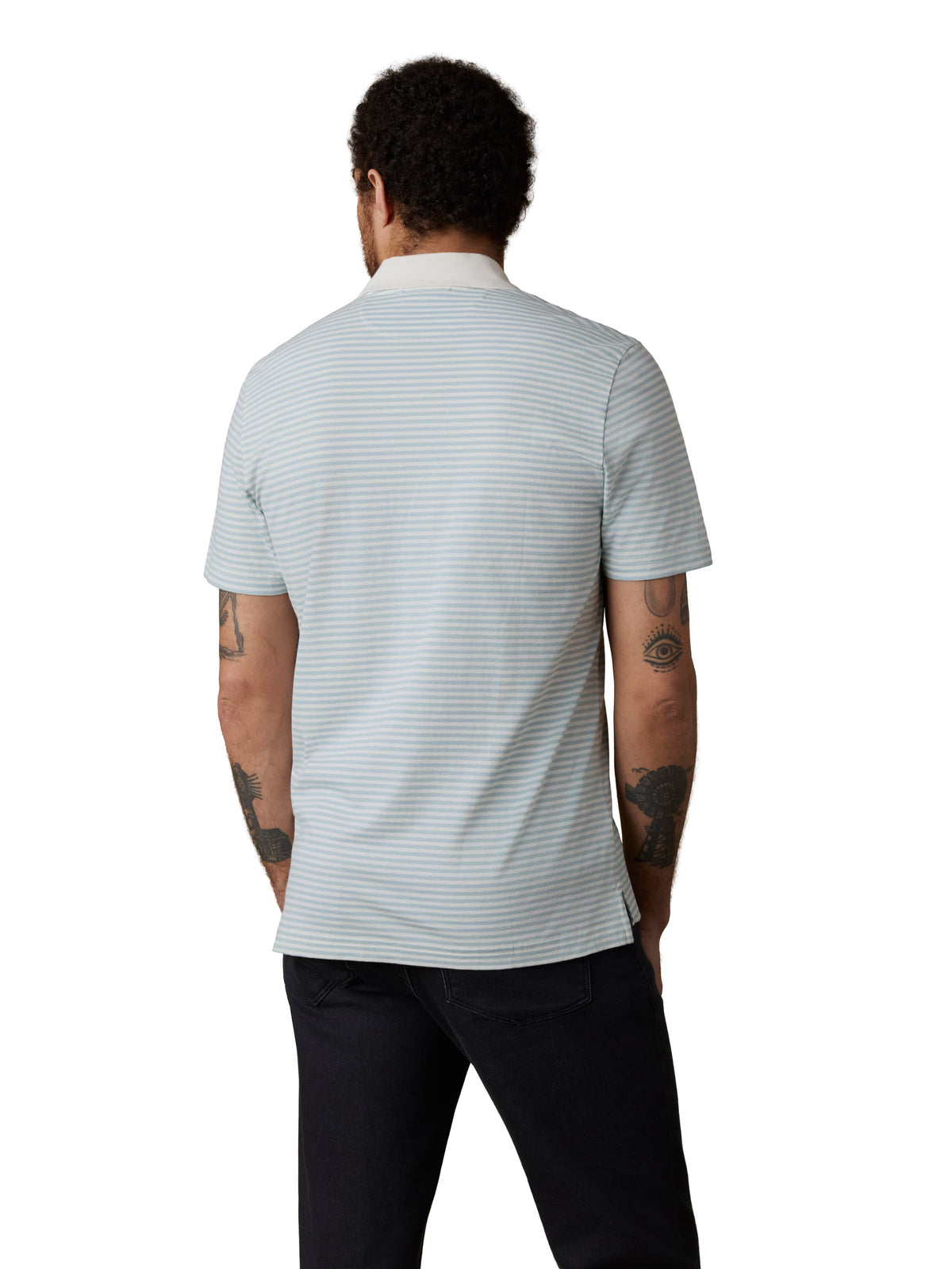 A man viewed from behind wearing a light blue striped polo shirt and dark jeans, image 3 of 3