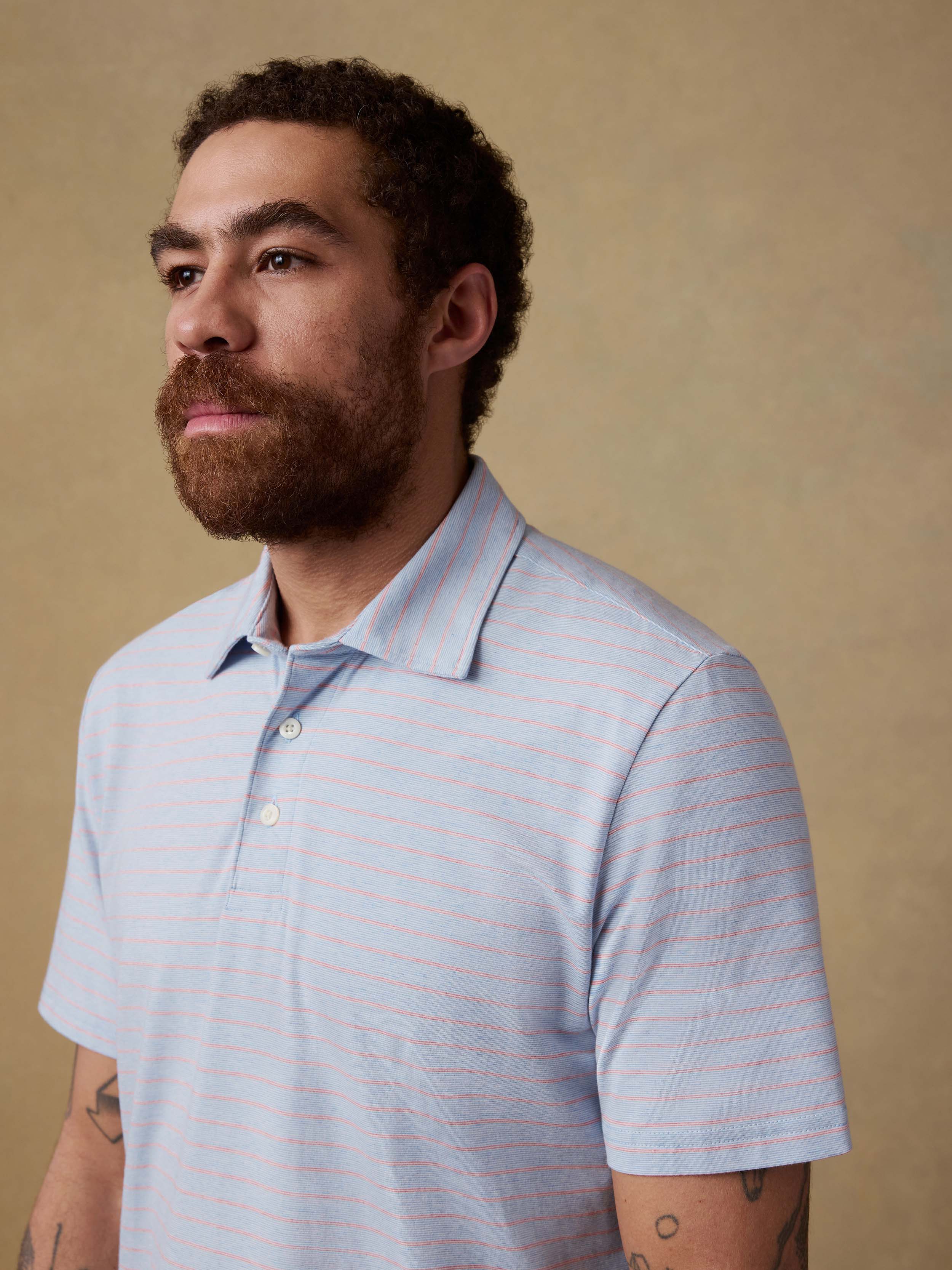 Man wearing a light blue polo shirt against a beige background