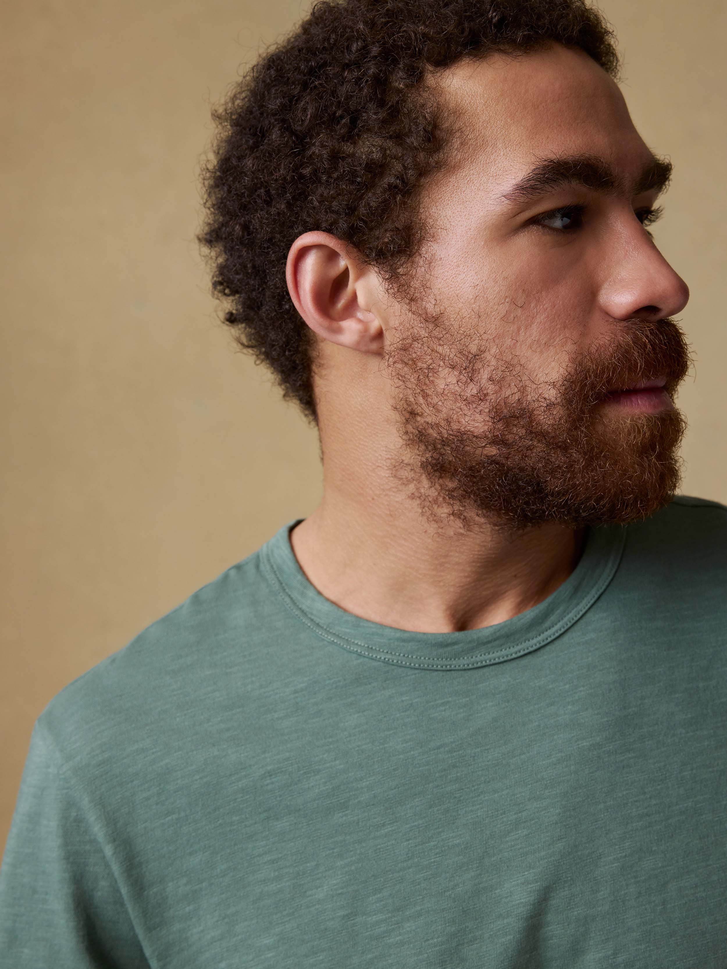 Man wearing a green t-shirt against a beige background